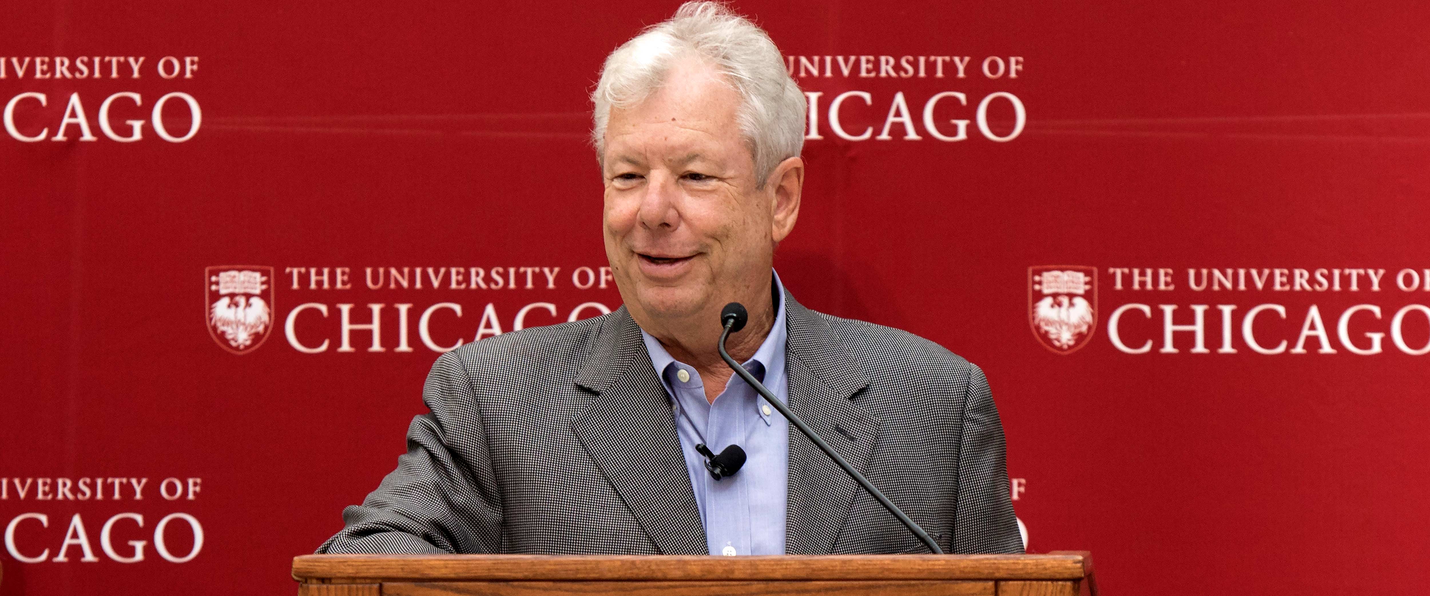 Richard Thaler speaking at a podium during his Nobel Prize press conference in 2017