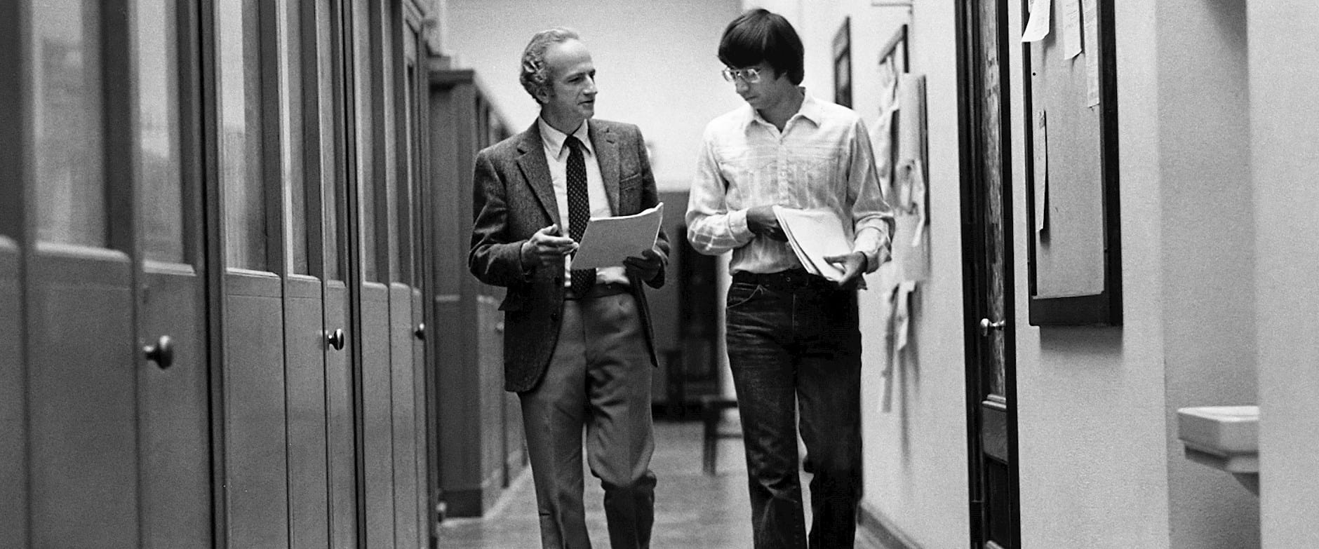 Gary Becker walking with a student down a hallway