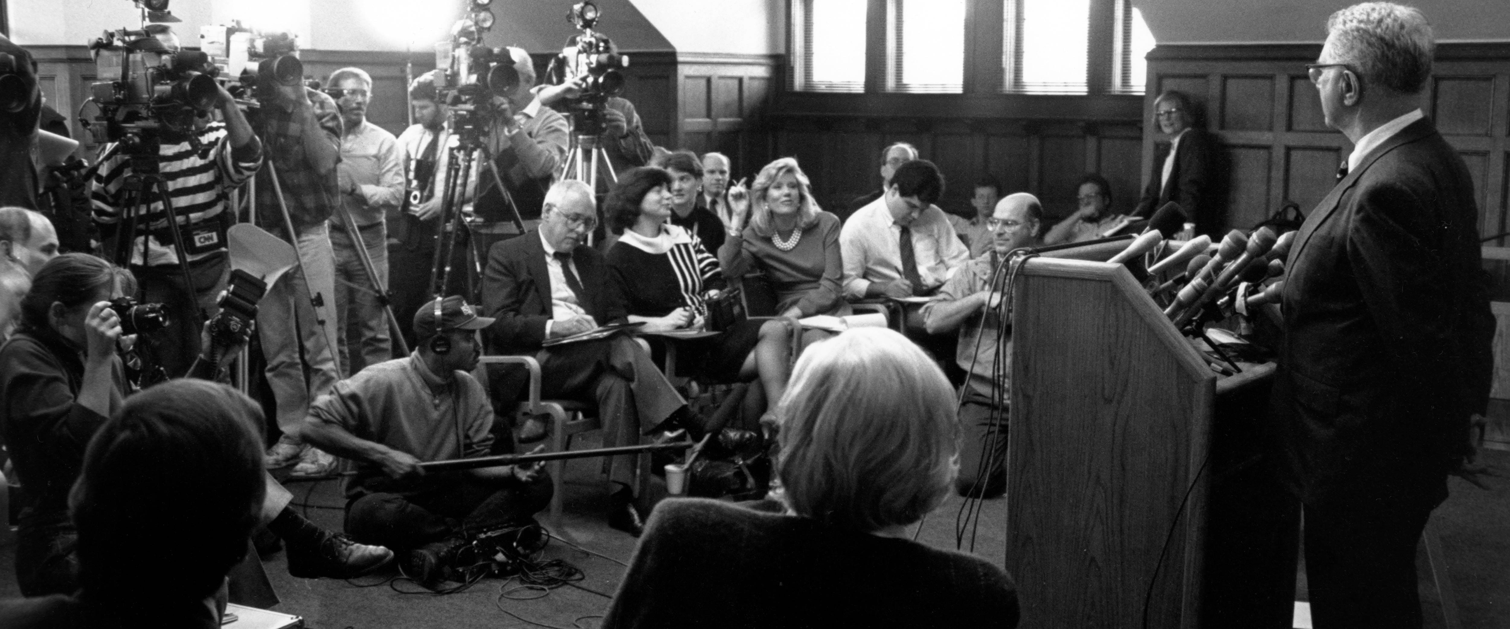 Merton Miller speaks to a crowd of television crews and reporters after the announcement of his Nobel award