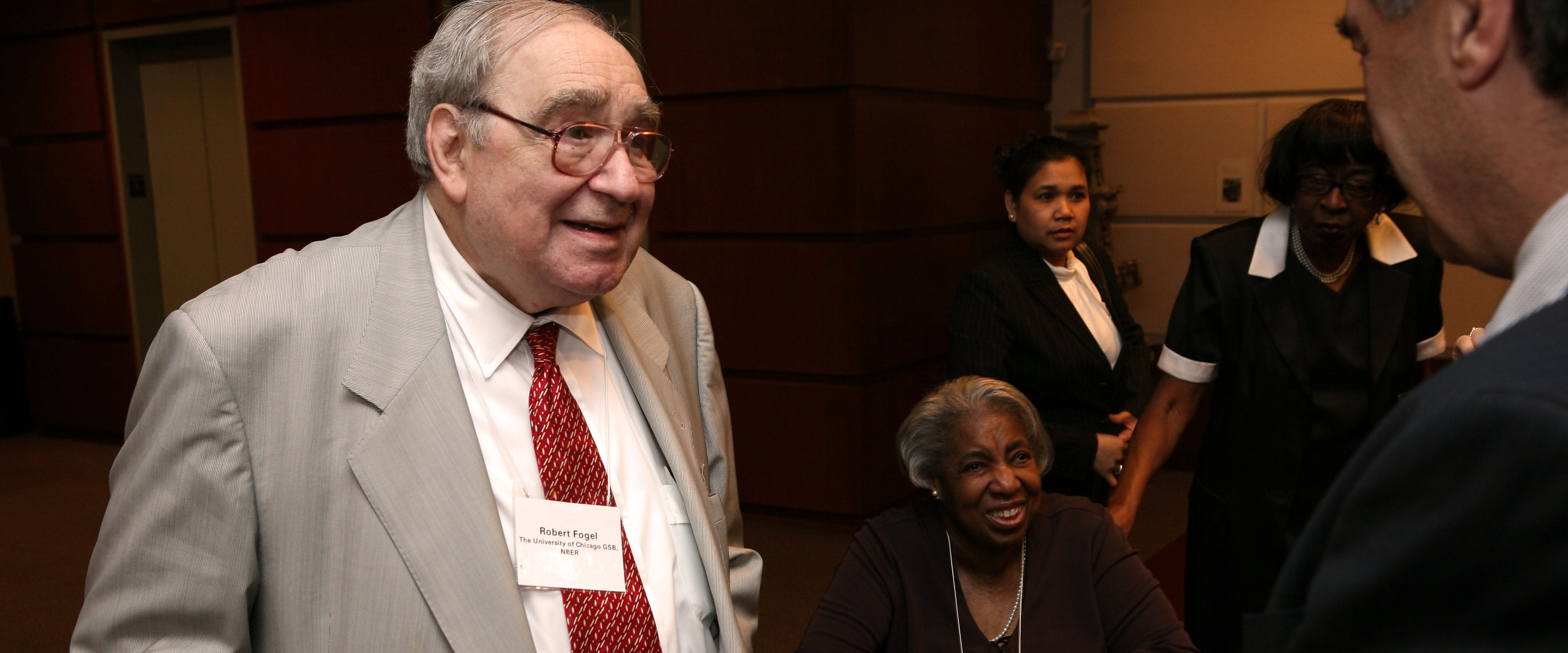 Robert Fogel meets with a group of people while wearing a nametag