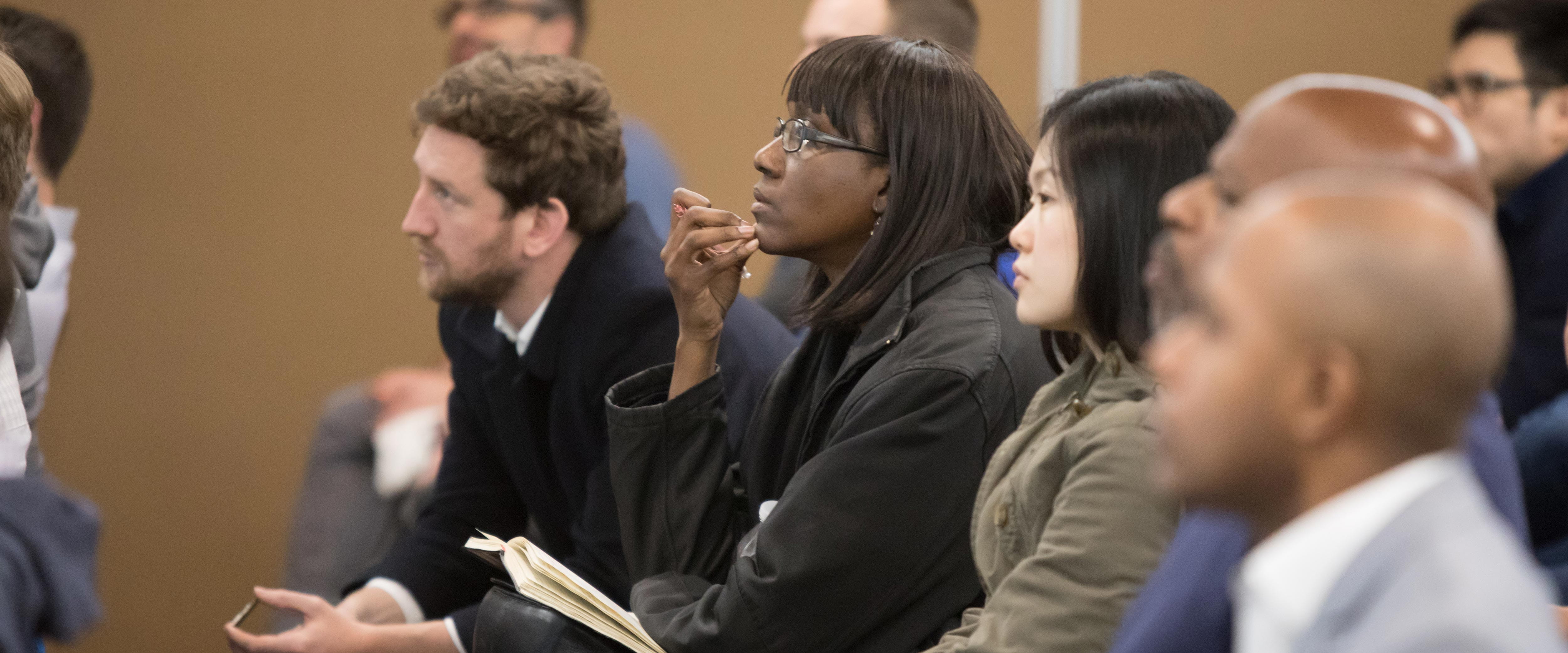 Audience members listening attentively while seated in a row