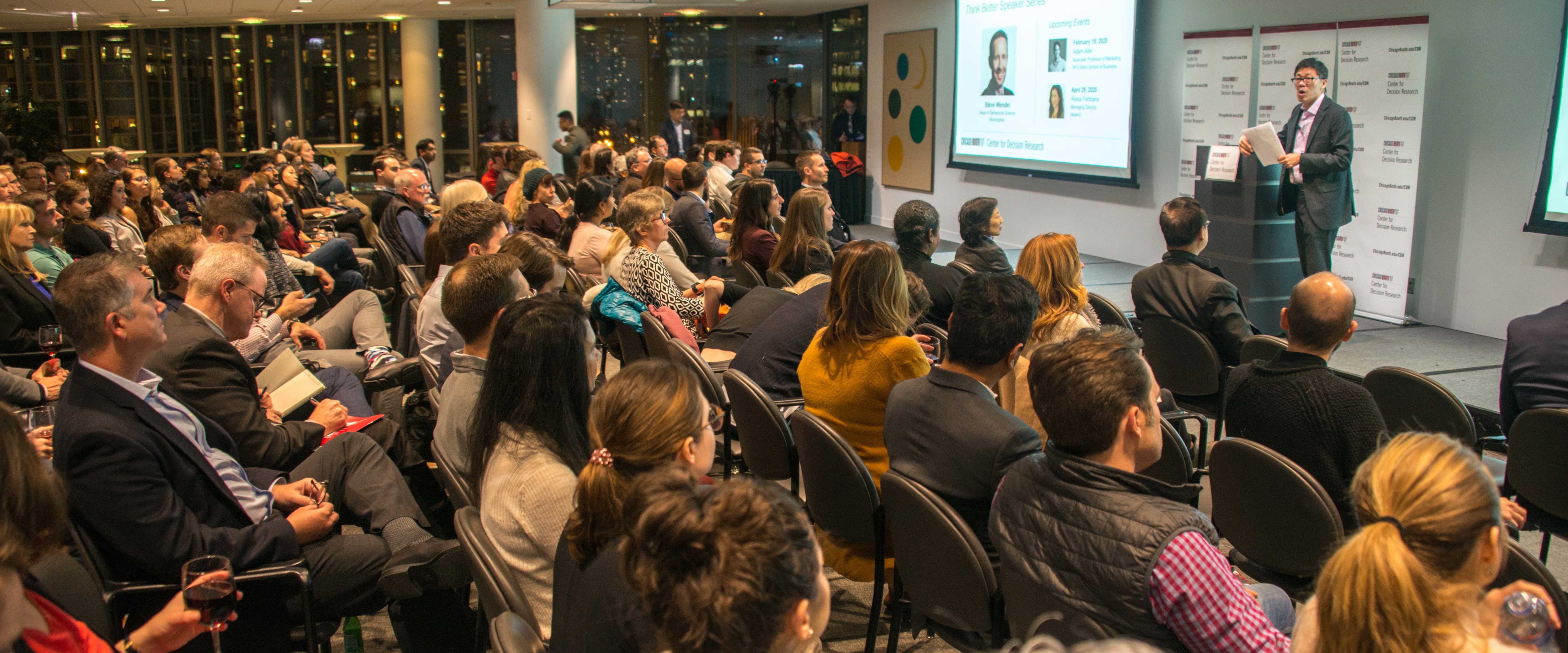 Large audience listening to a speaker at the front