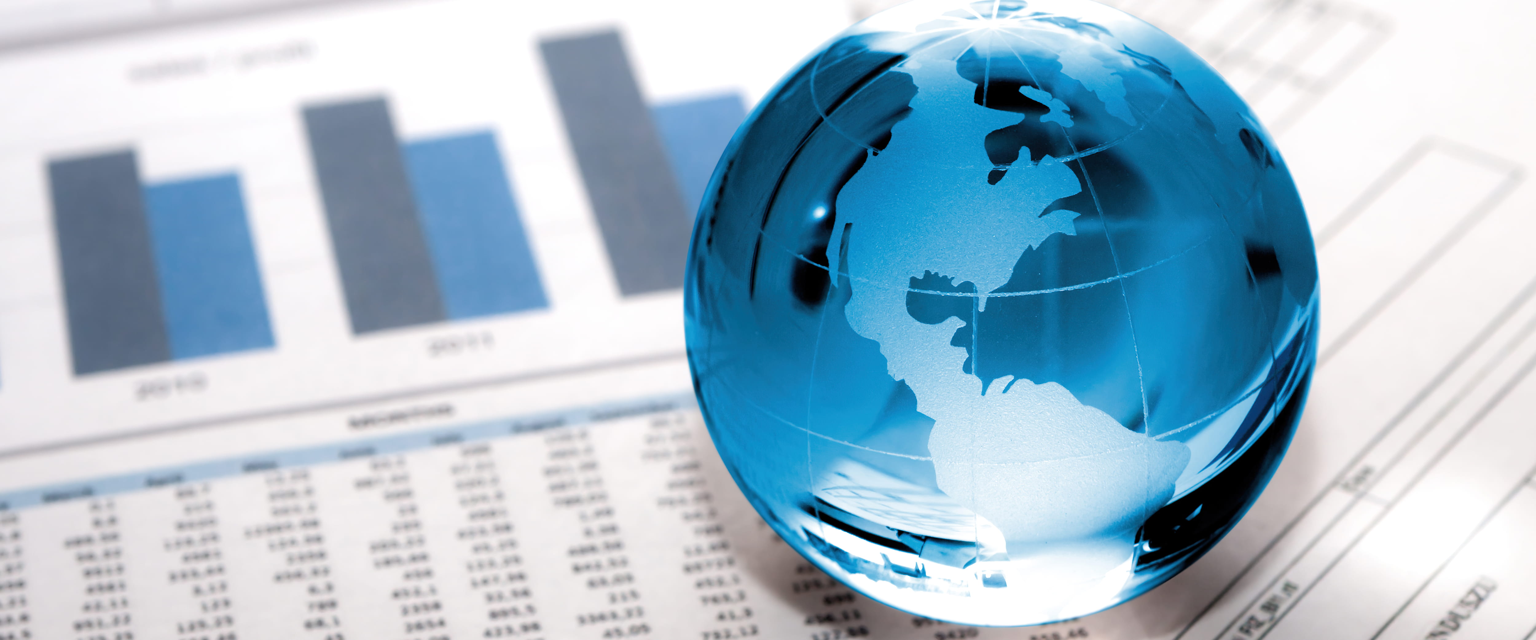 Glass globe on top of charts and financial papers