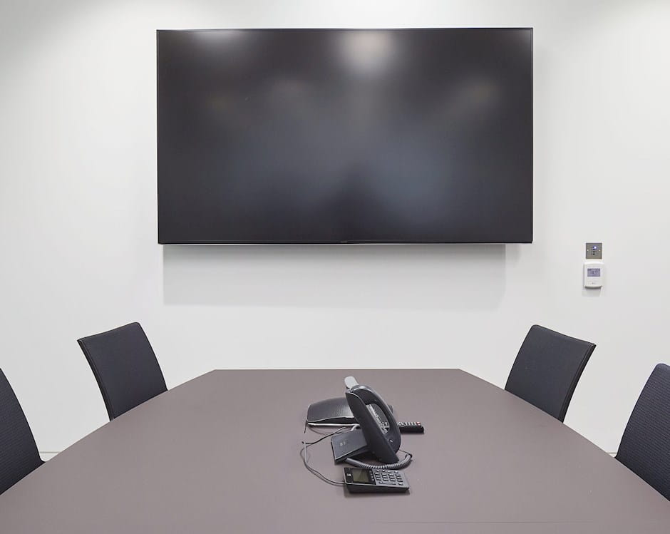 Private office with a television and conference table with a phone