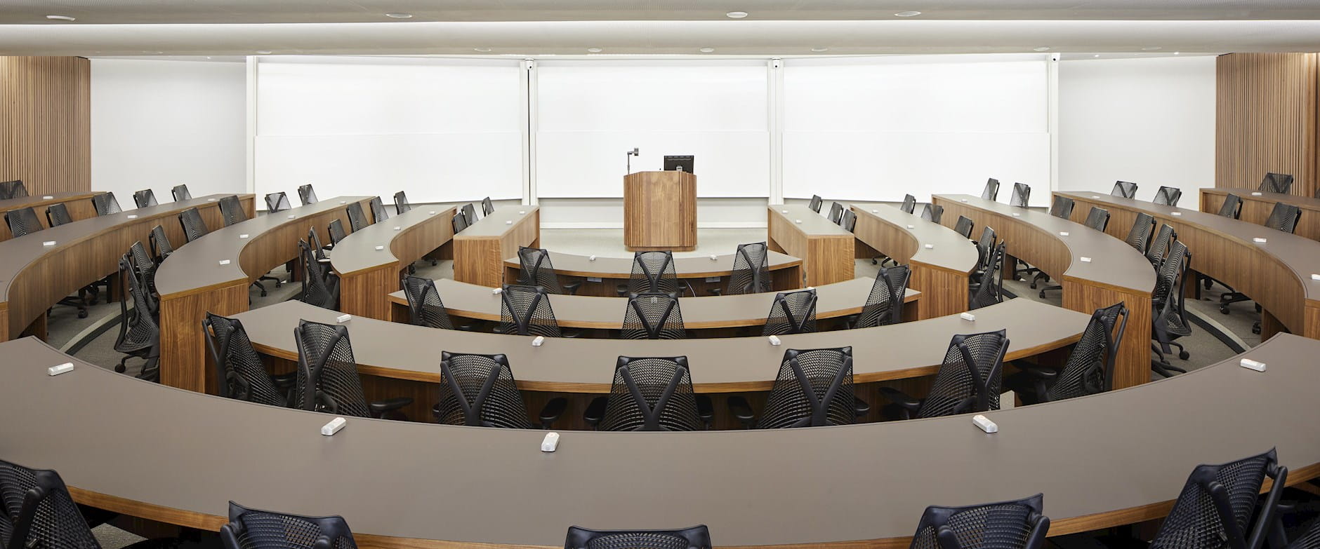 Large semi-circular conference hall with desks around a central podium