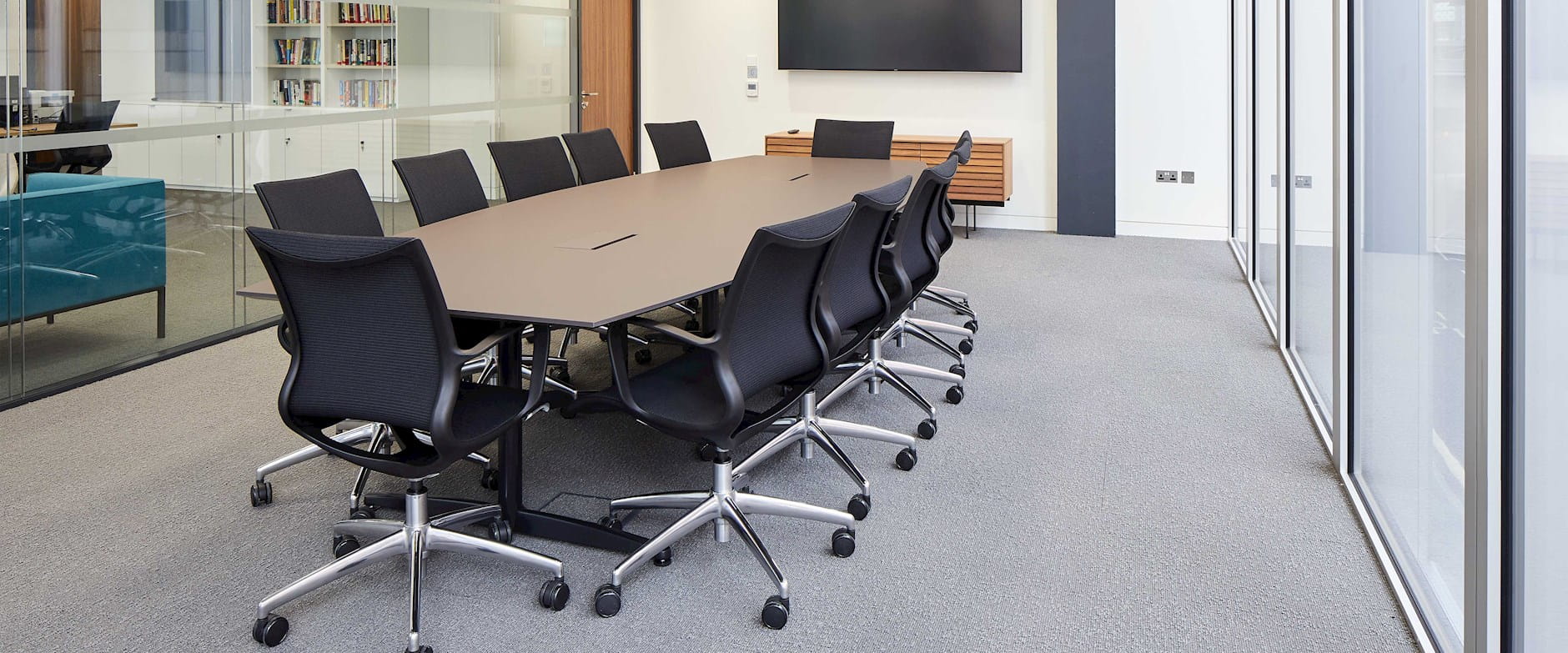Faculty conference room table with screen on the wall and black chairs around the table
