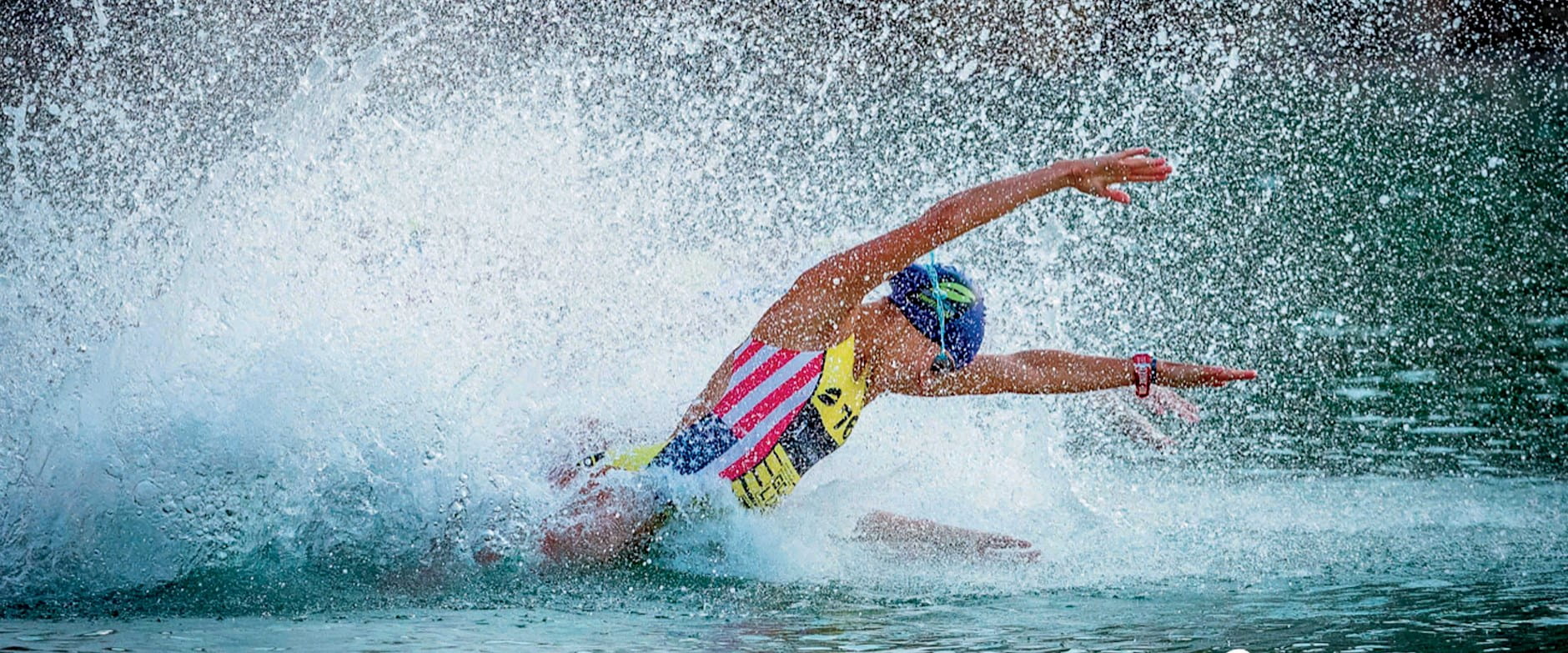 Woman in United States flag swimsuit diving through water
