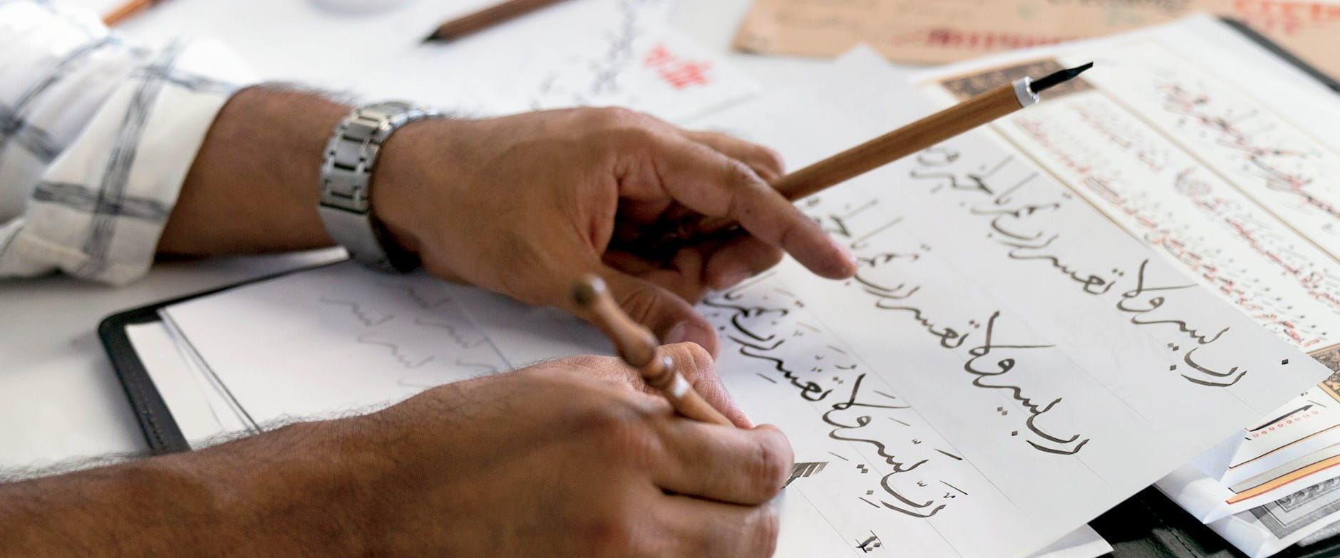 Zeeshan Farooq writing calligraphy into a notebook