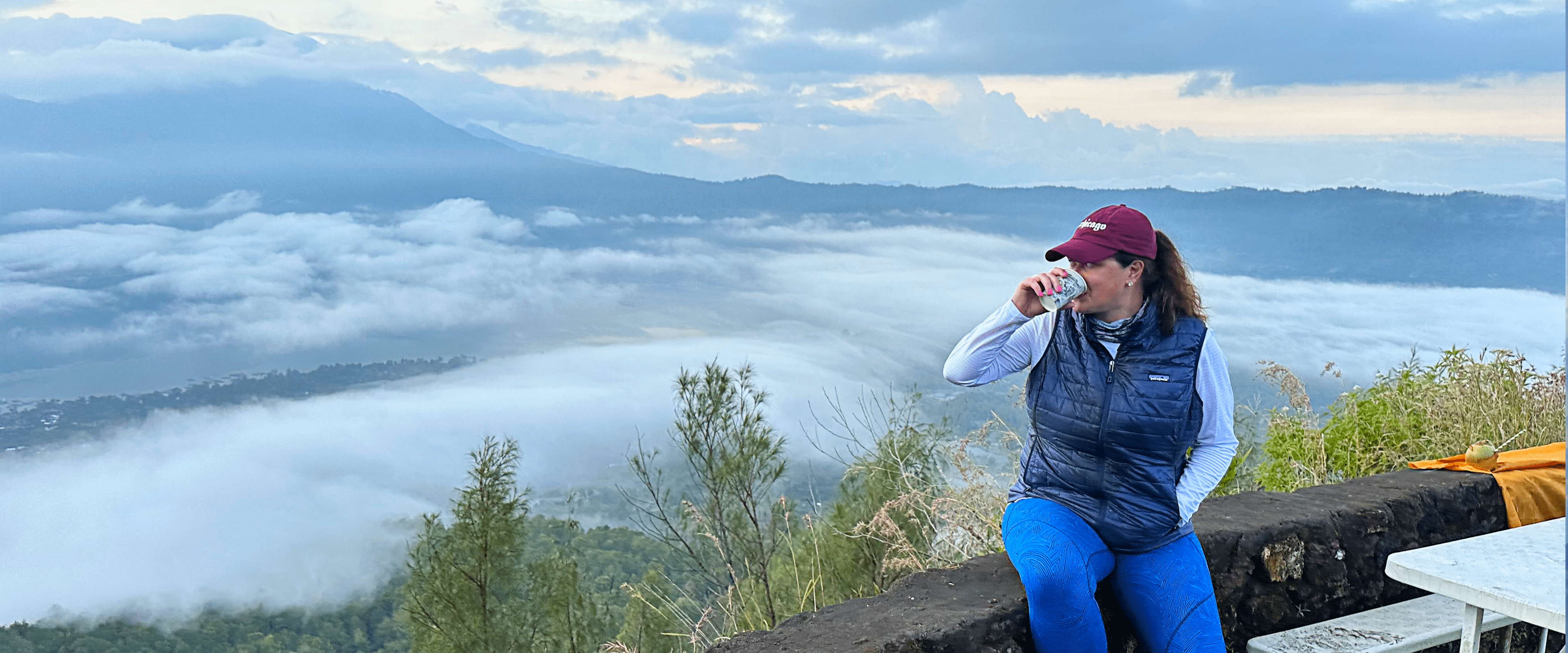 Kate Volzer sitting atop a mountain with a foggy valley below.