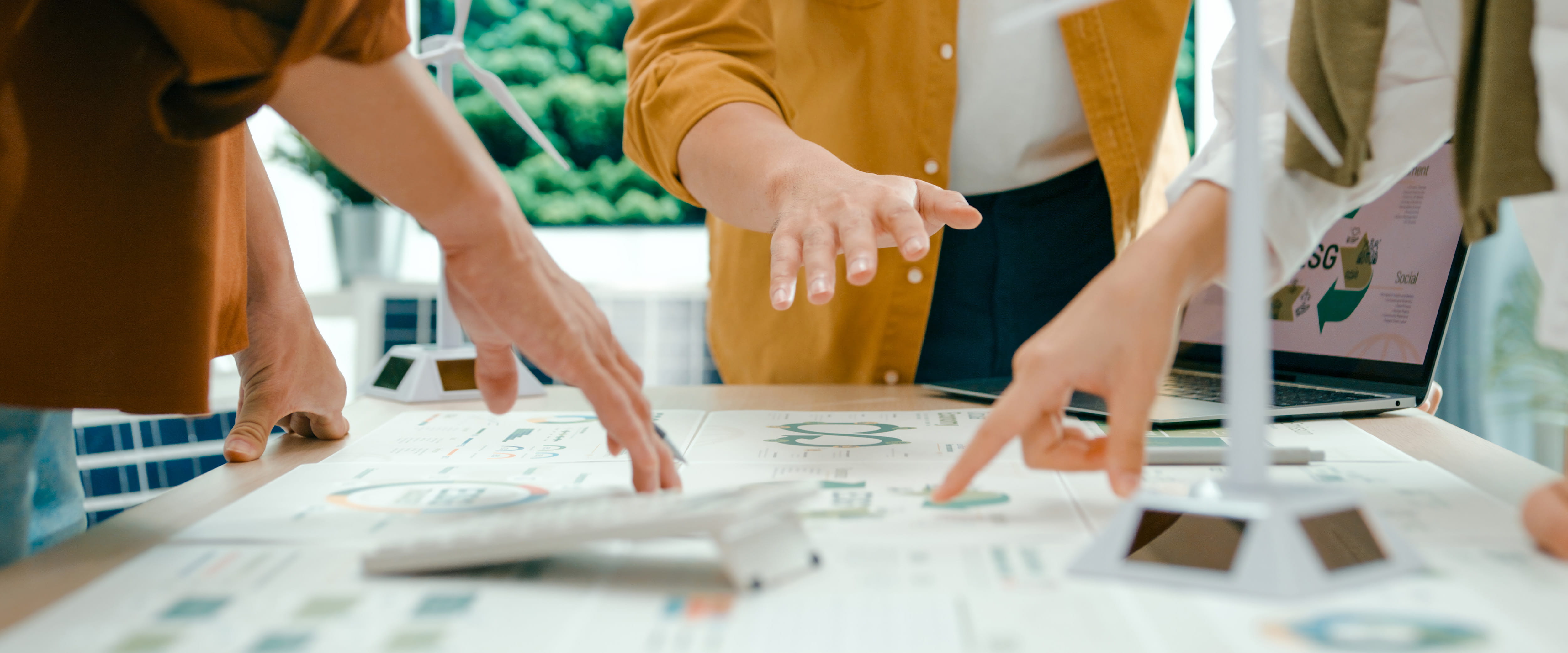 A closeup of hands pointing at papers on a table.