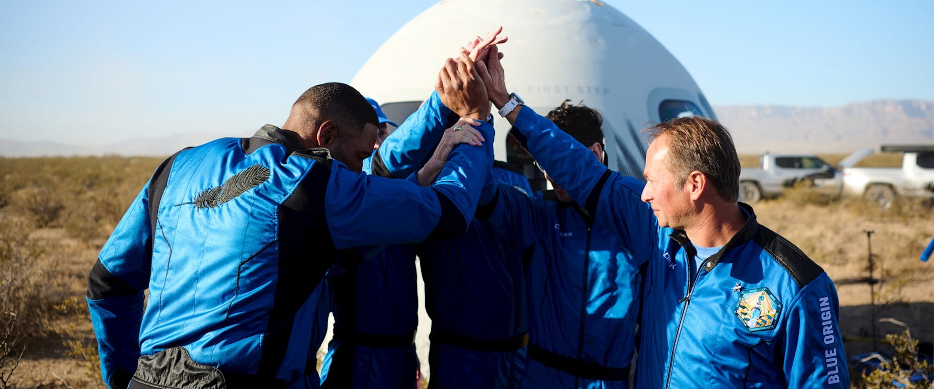 Members of Blue Origin's space exploration program putting their hands together for a team huddle