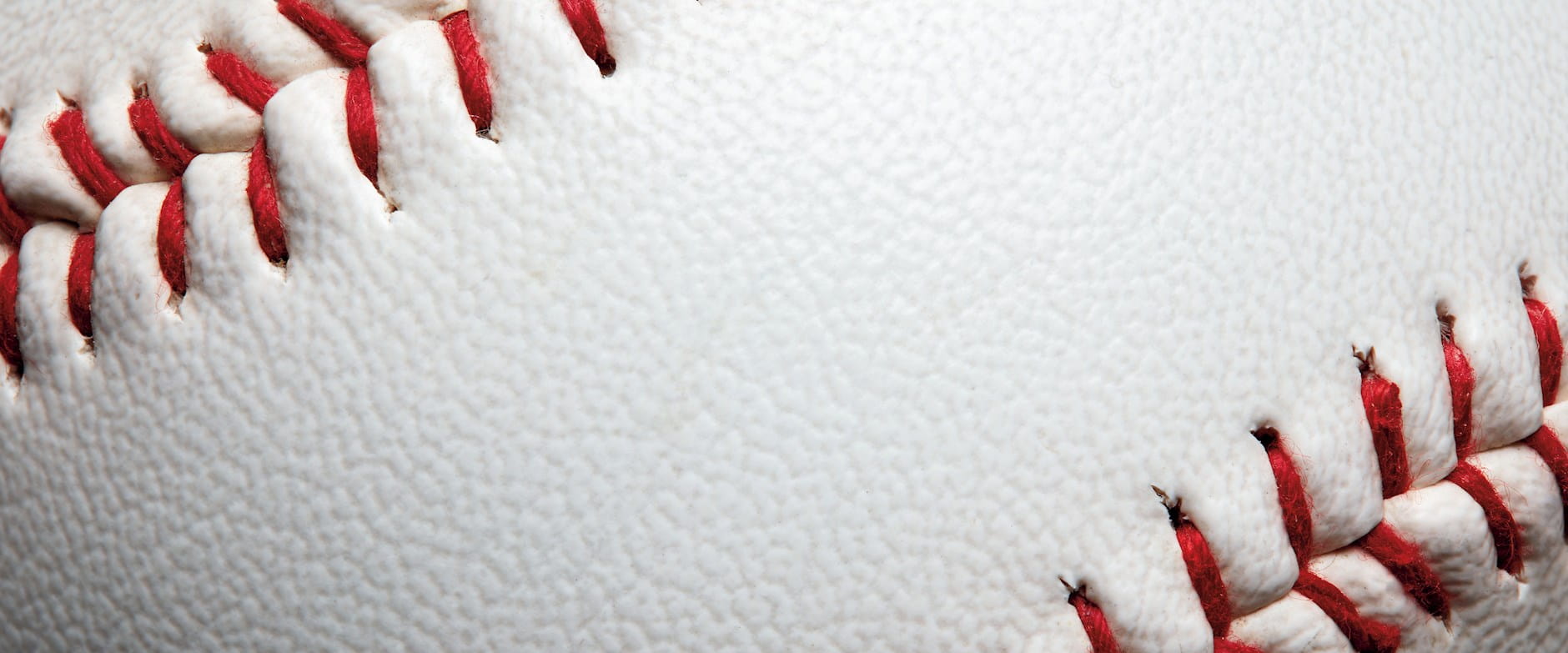 Extreme close up of a white baseball with red stitches
