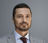 A headshot of Amir Sufi against a gray background