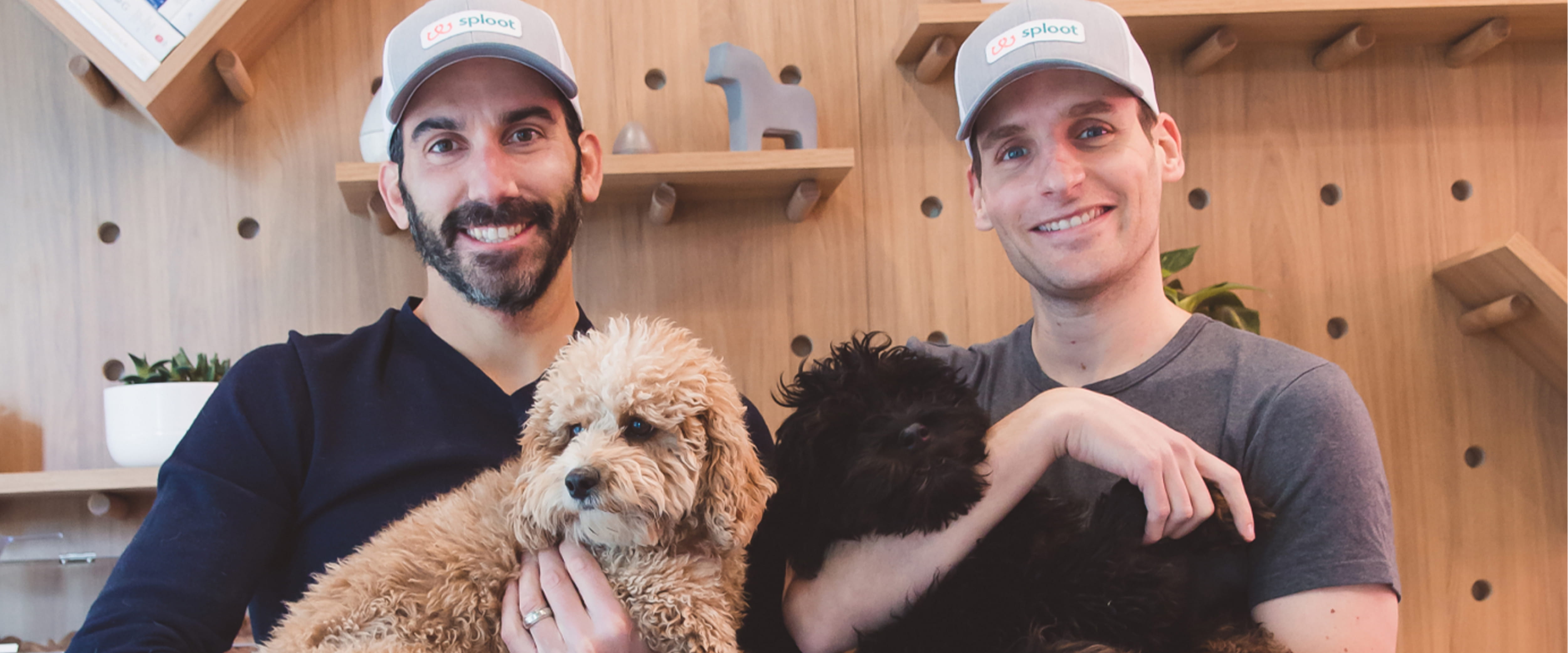 two men in hats holding dogs