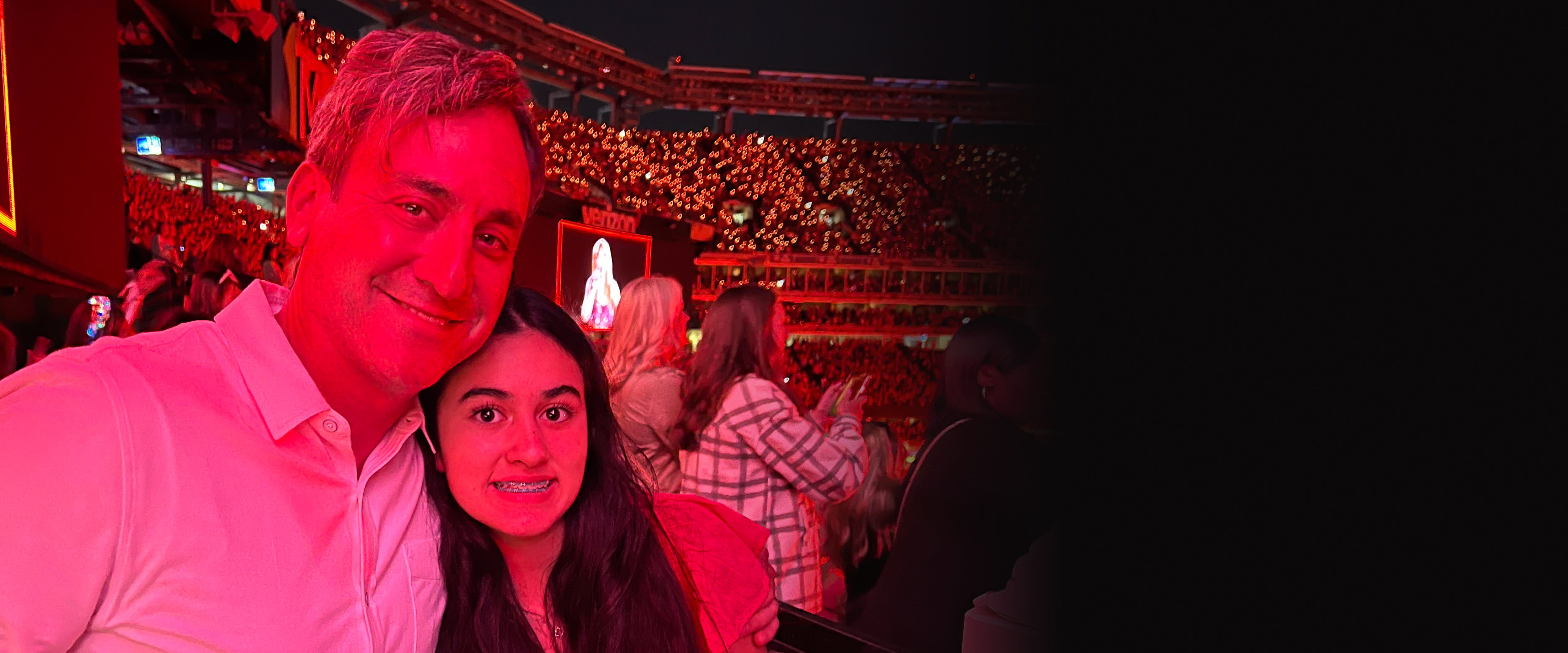 Levin and his daughter in red light in a concert crowd.