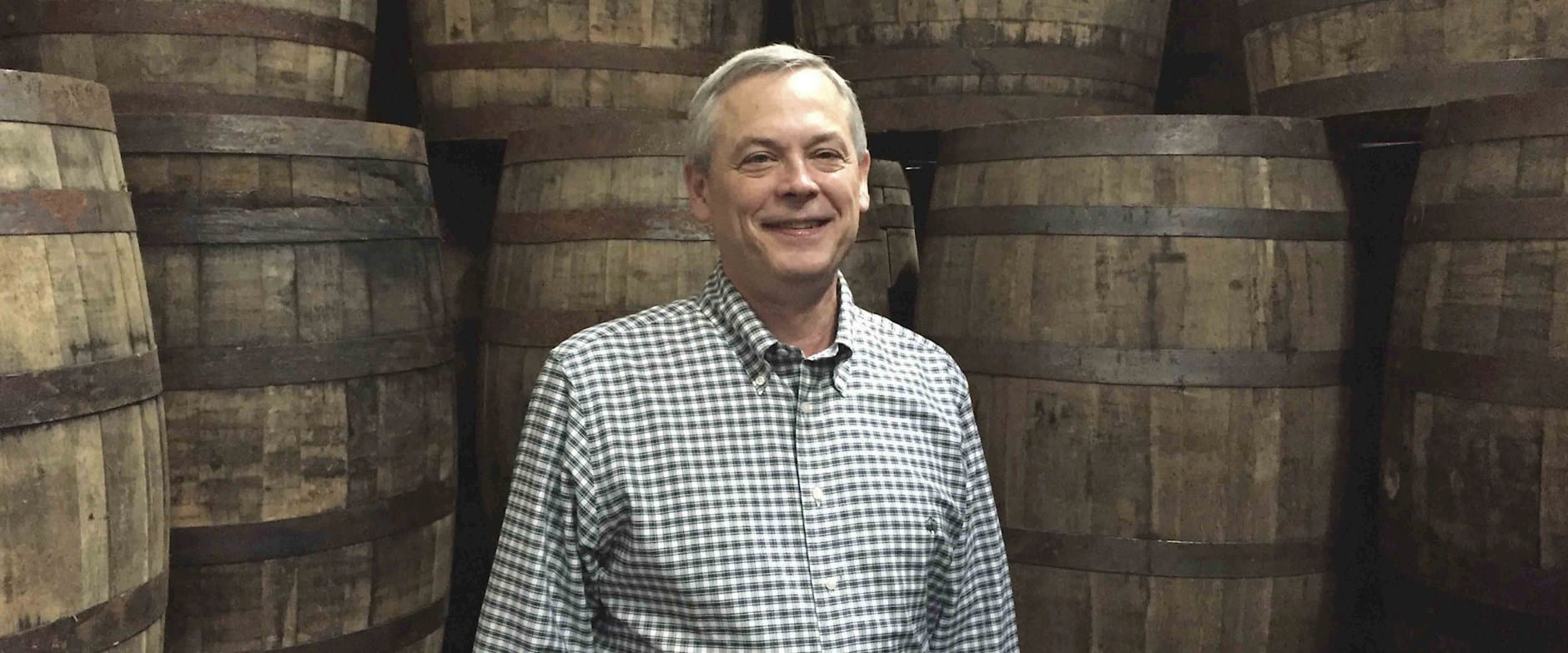 Tom Jensen standing in front of whiskey barrels 
