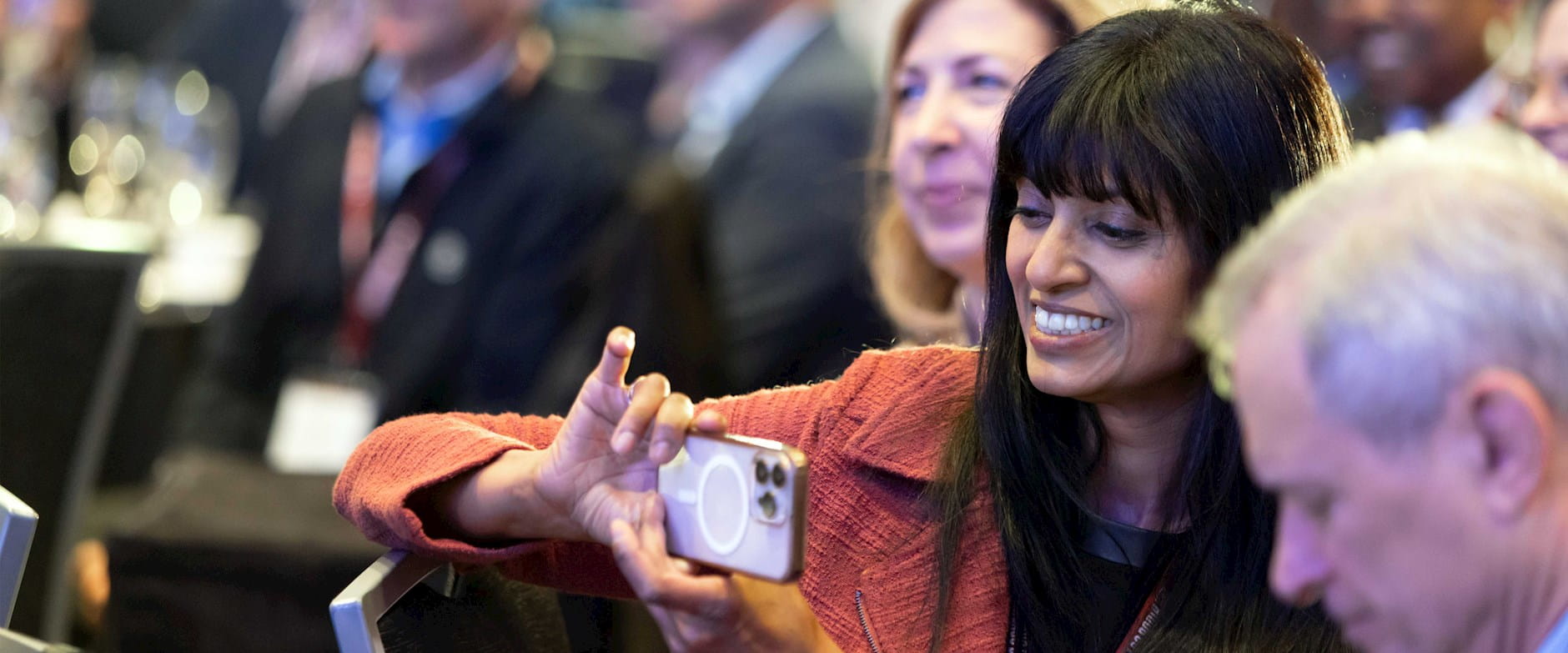 An audience member taking a photograph with a smartphone