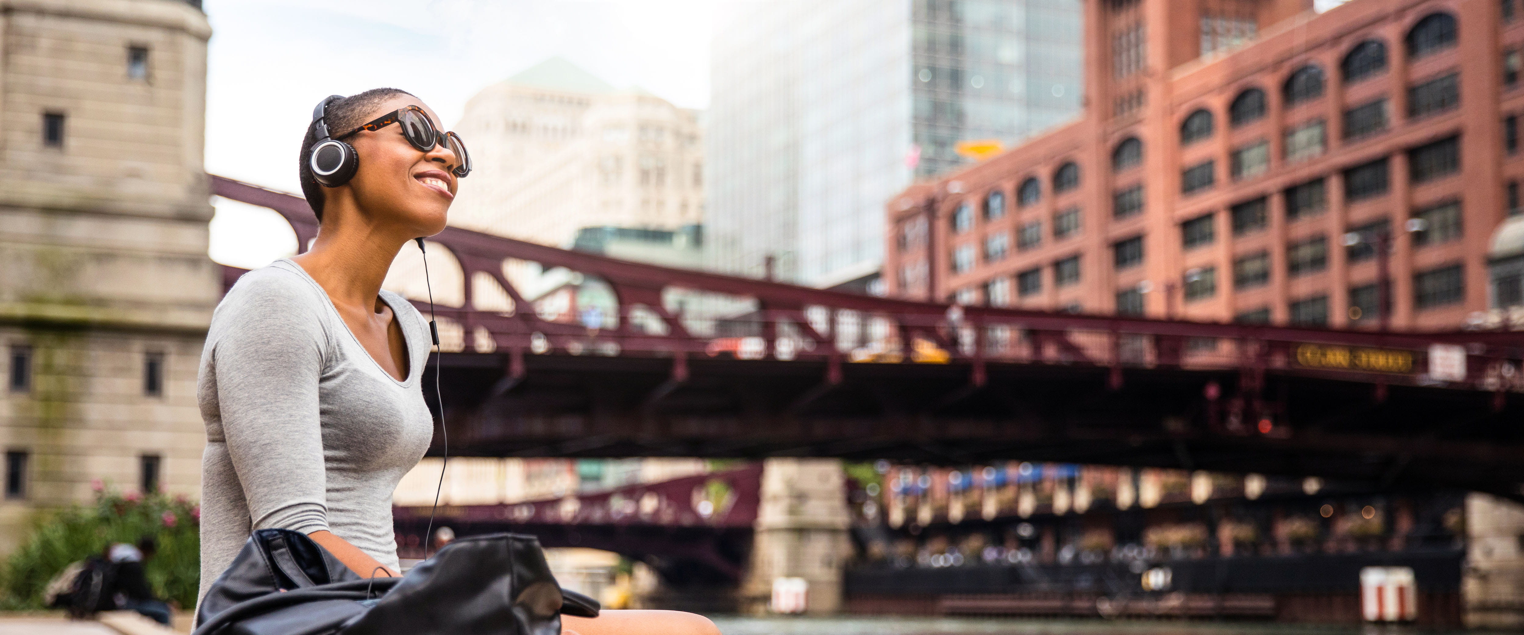 Person sitting on the edge of the Chicago River smiling and listening to music