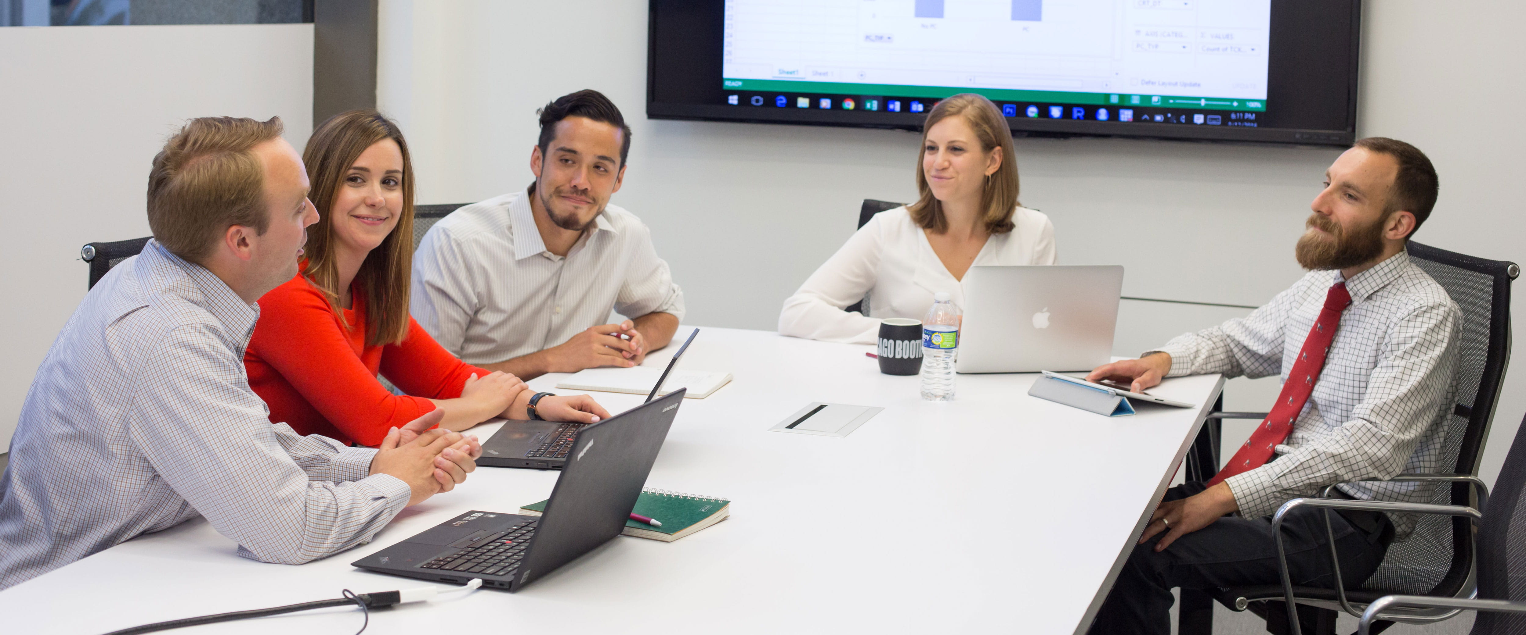 Group of male and female students working together on laptops in the Harper center