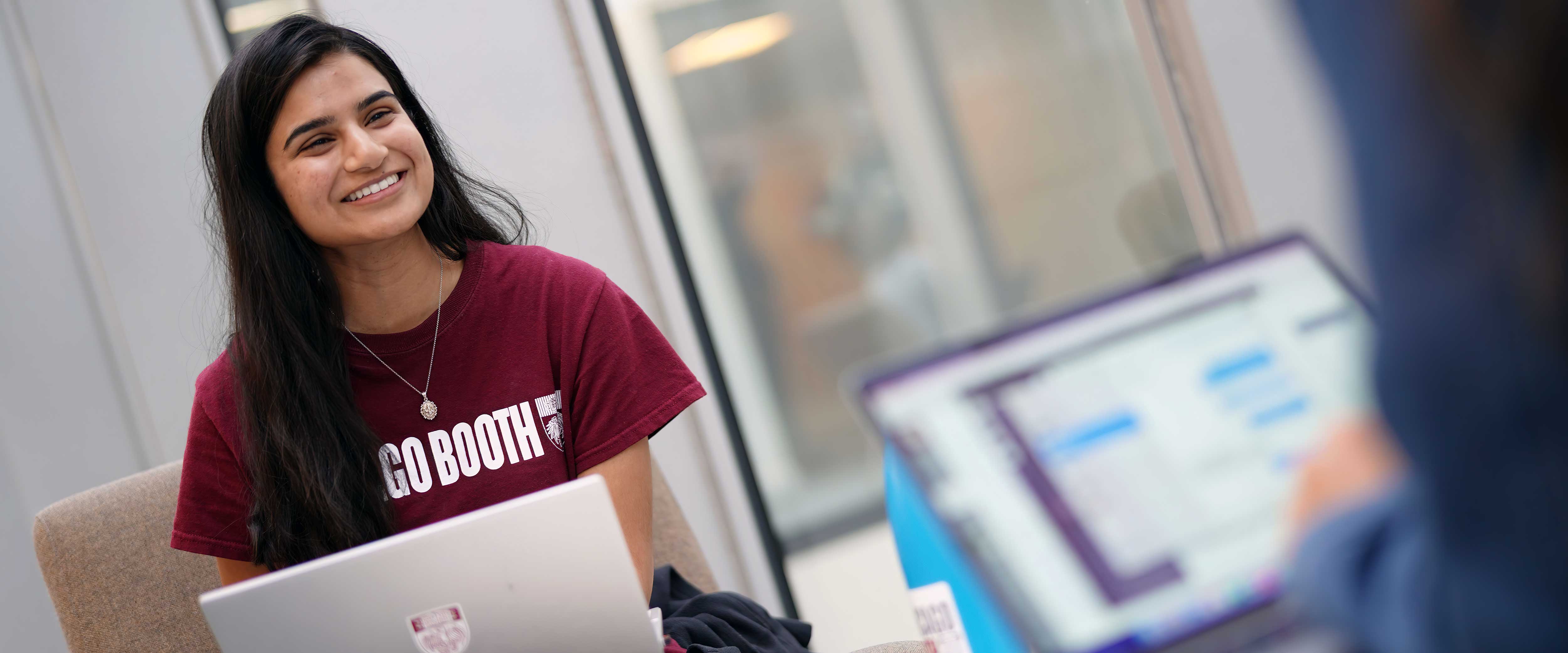 A young woman with a laptop smiling at a companion
