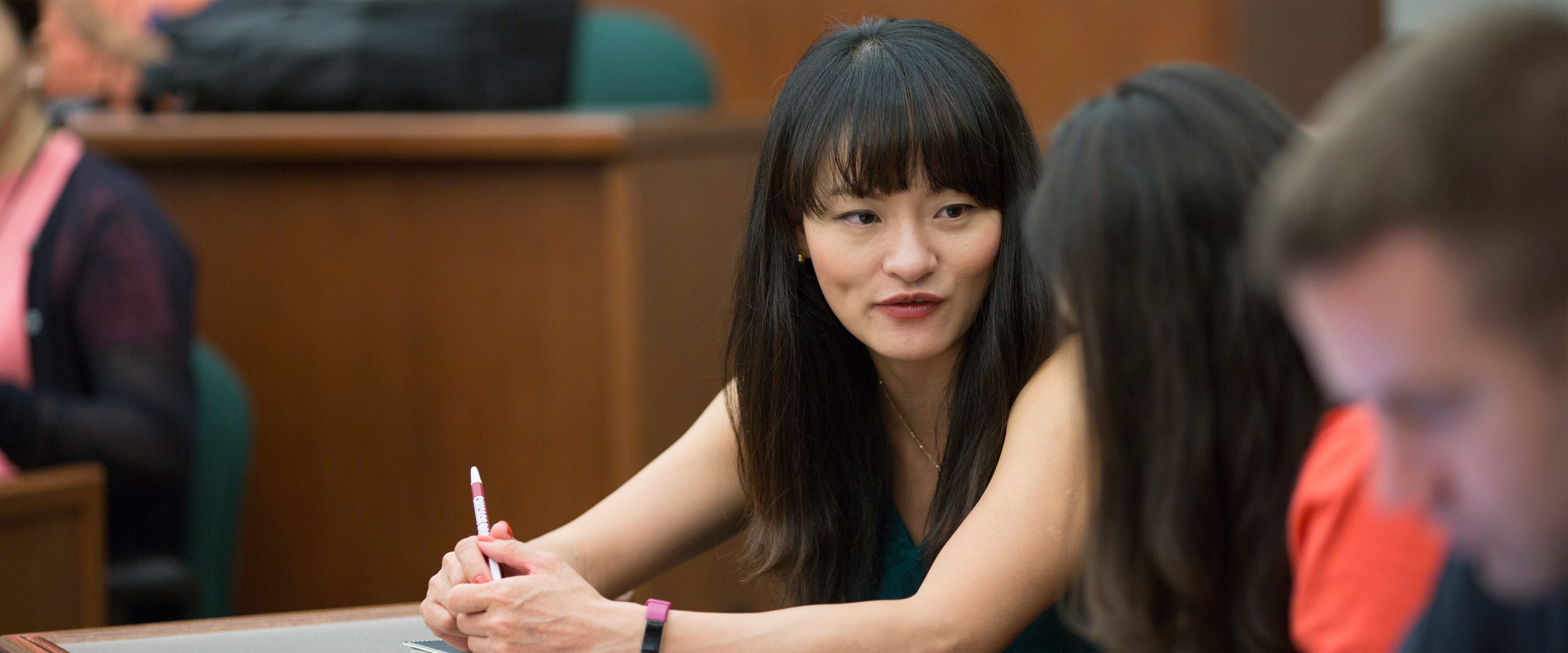 Two female students sitting and chatting to each other in class