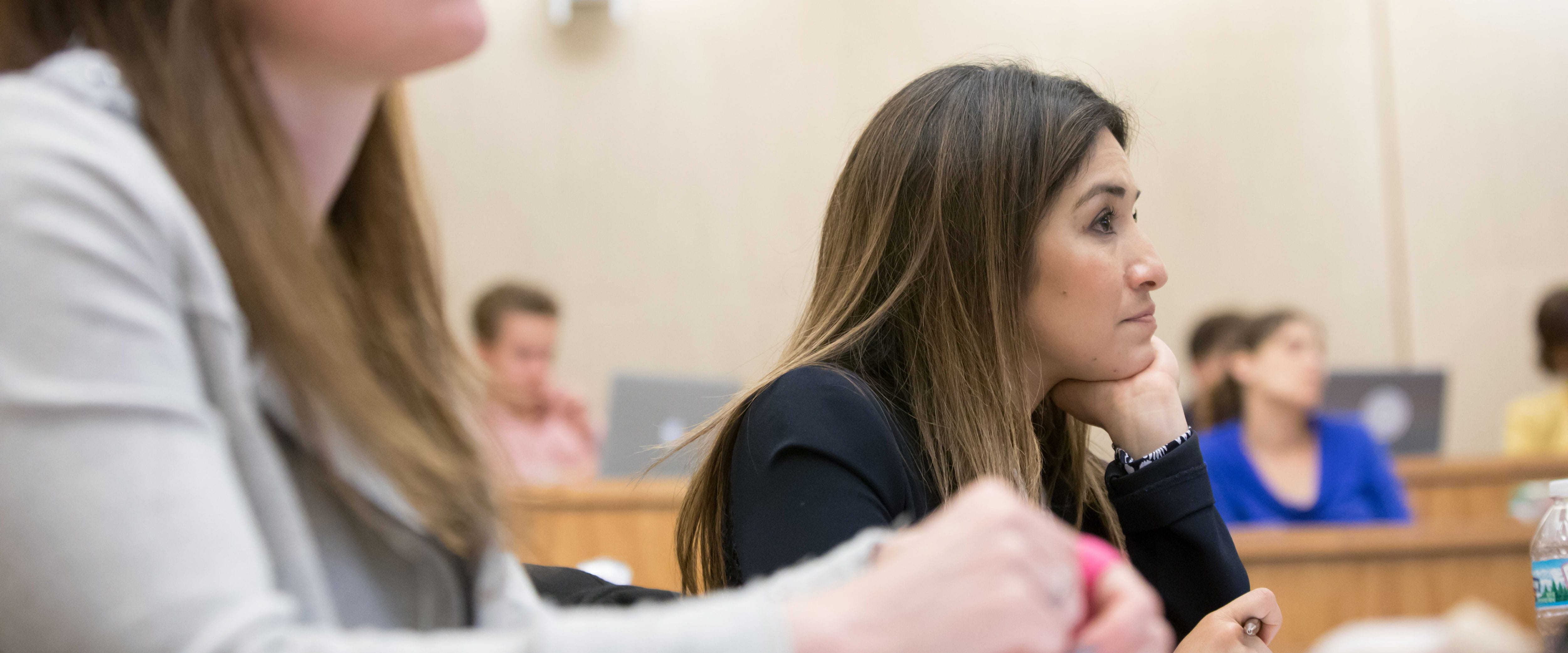 Female student sitting in class, listening with her chin resting on her hand