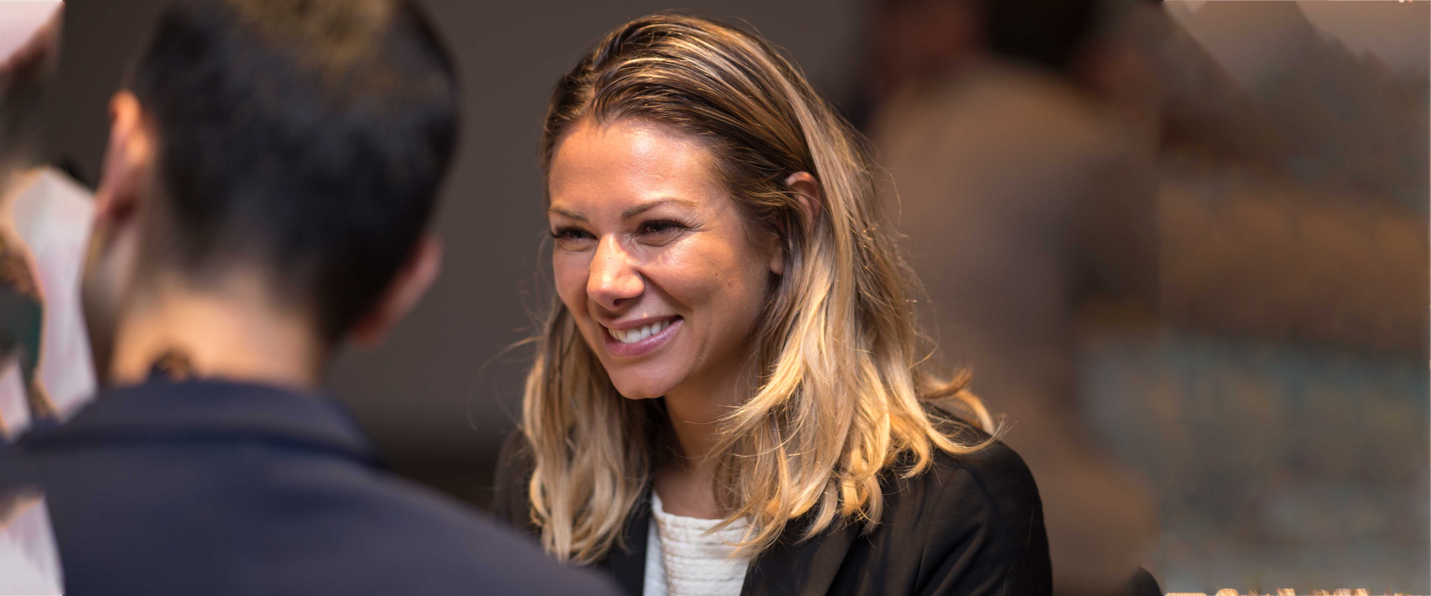 woman speaking to two men and smiling
