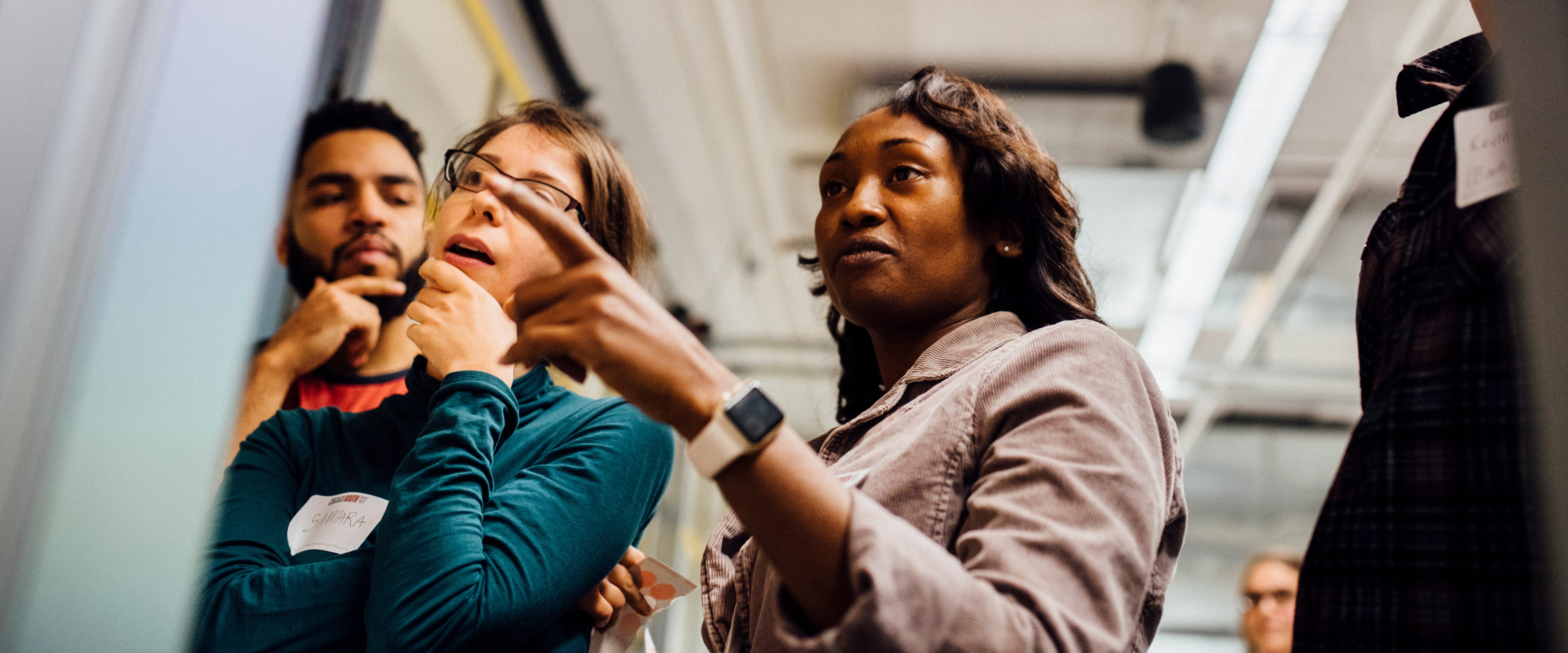 woman pointing to board during team discussion