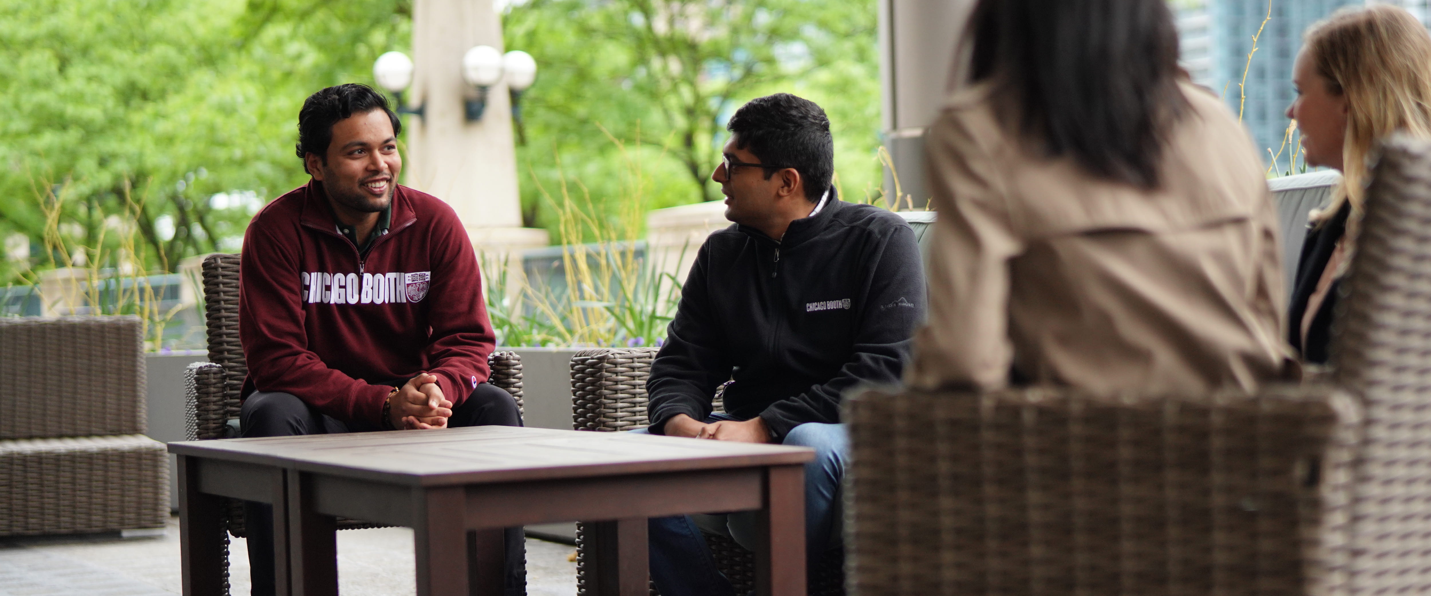 Student smiling and talking with other students outside Gleacher
