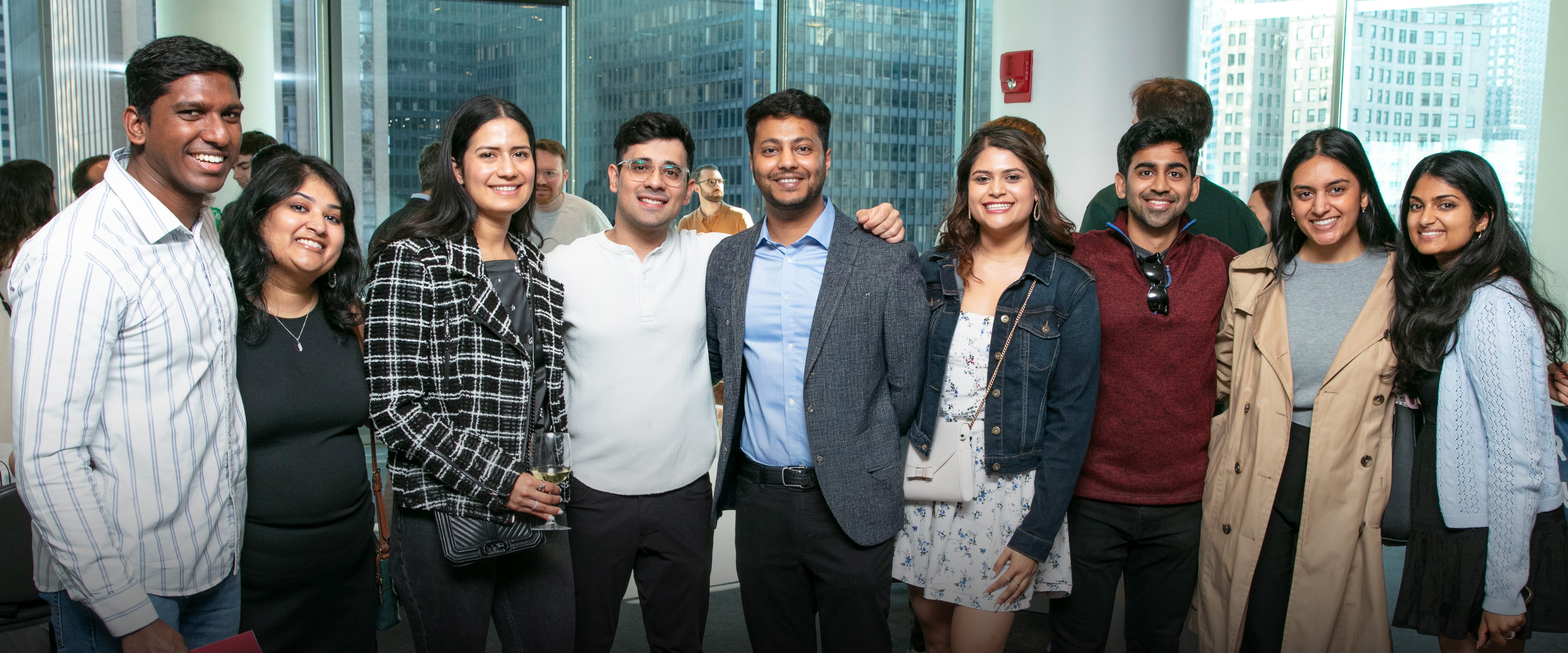 A group of smiling students at an evening networking event.