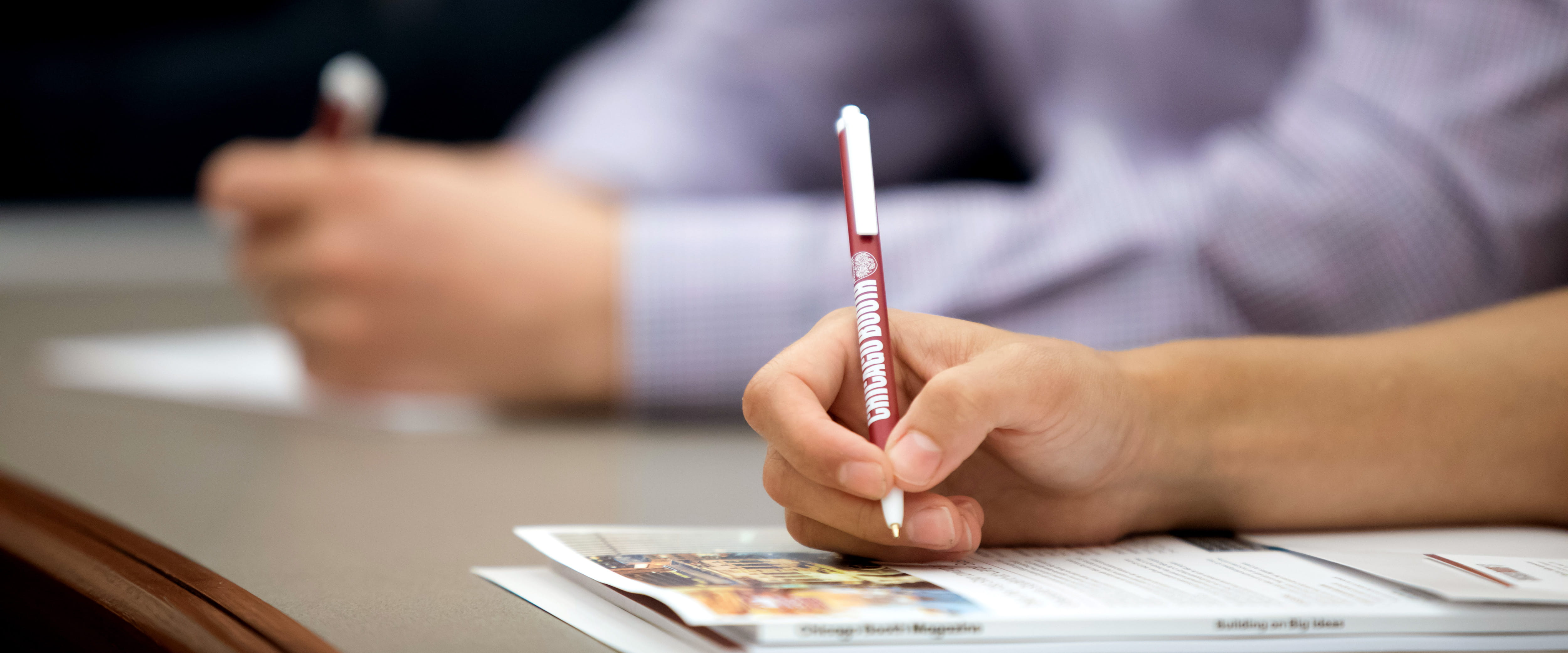  Student writing with a Chicago Booth pen