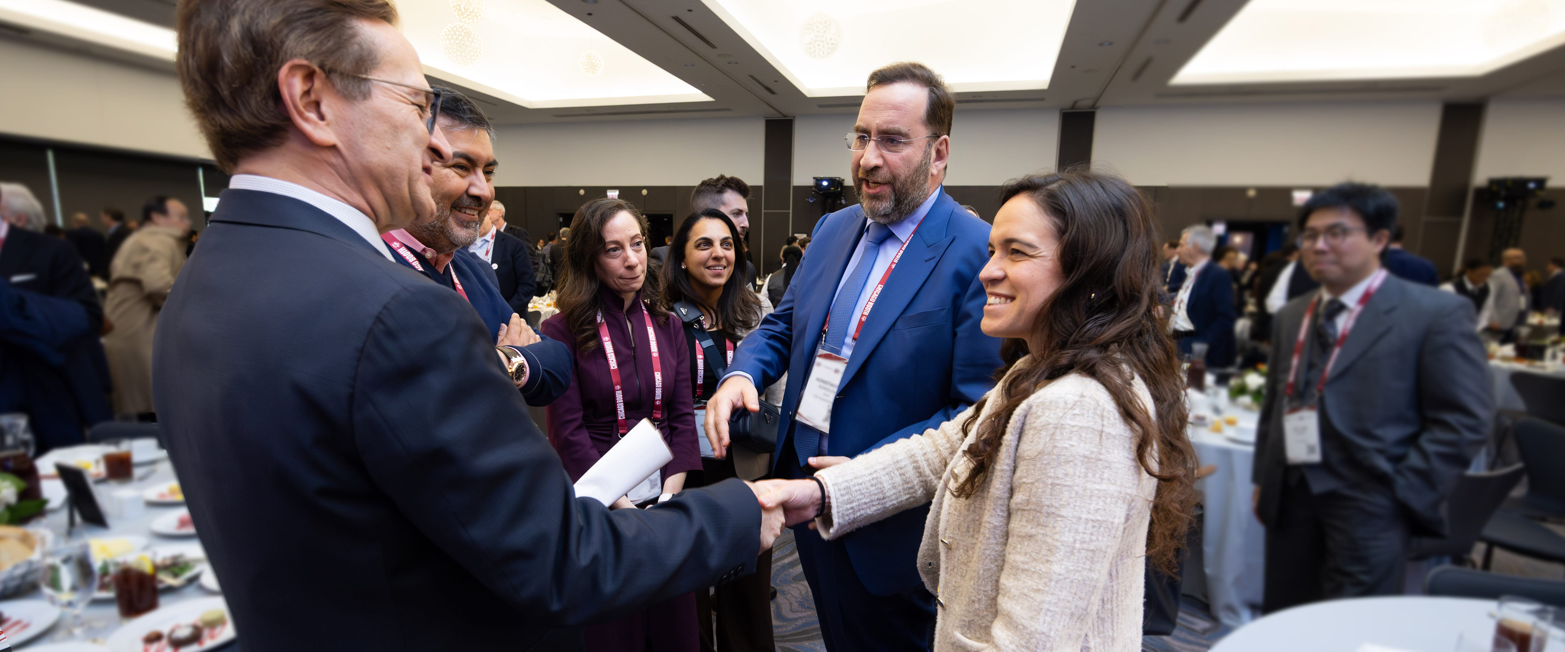 Student shaking hands with professor and meeting alumni at event
