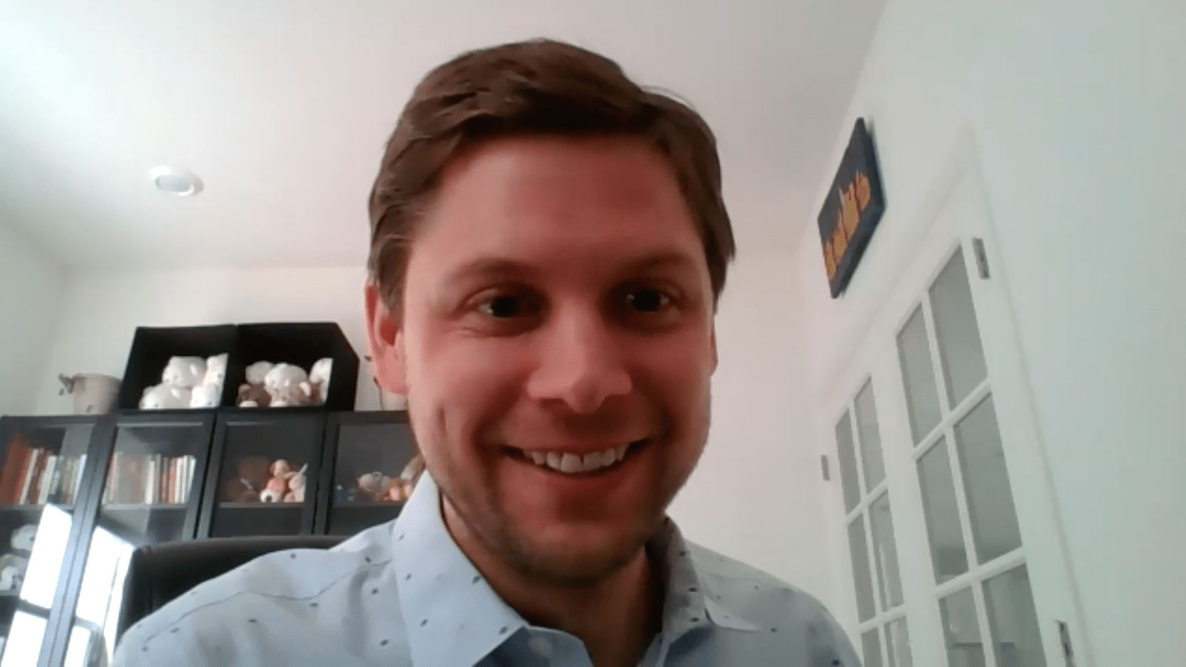 A Booth student smiles at the camera in a Zoom meeting format.