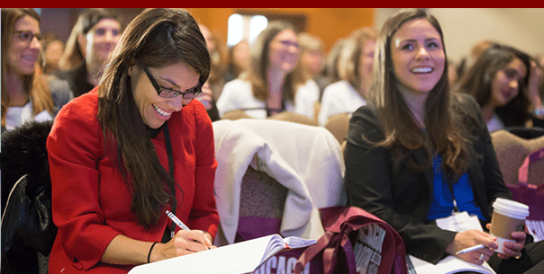 Woman taking notes and woman smiling in audience at Booth Women Connect Conference