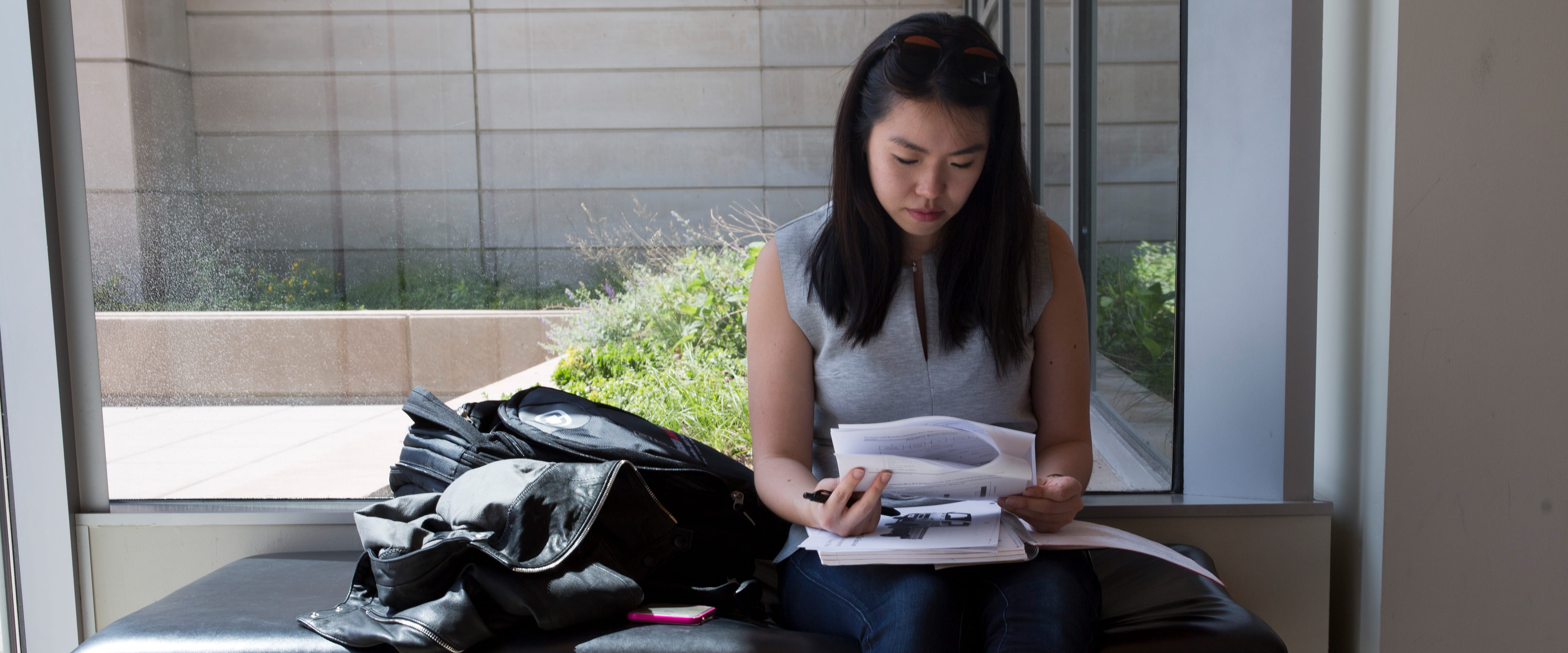 A woman looks sitting on a bench, looks at a packet of paper with a look of concentration