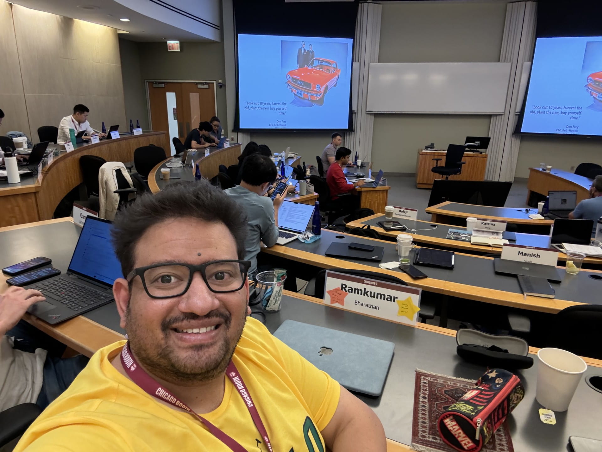 Man smiling at the camera with a classroom and other students behind him