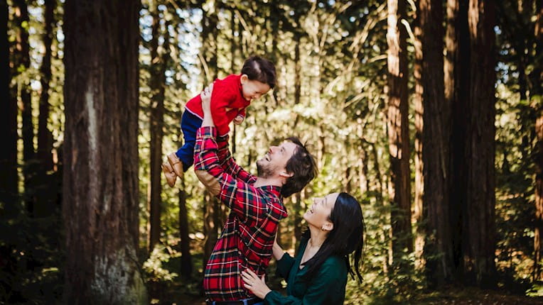 Stephanie Hwu and family lifting her child in the forest