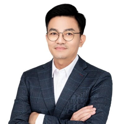 A man smilles at the camera with his arms crossed