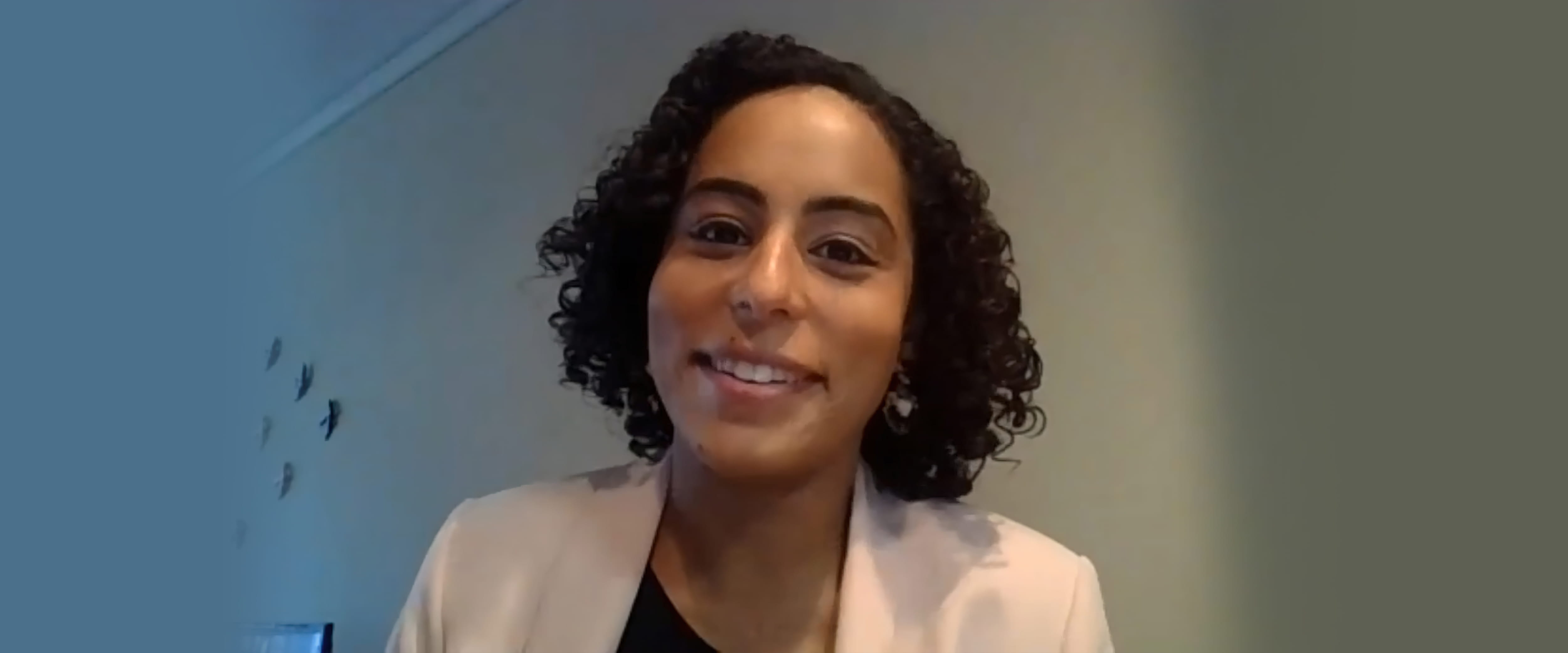 Smiling woman with curly hair in a cream colored blazer