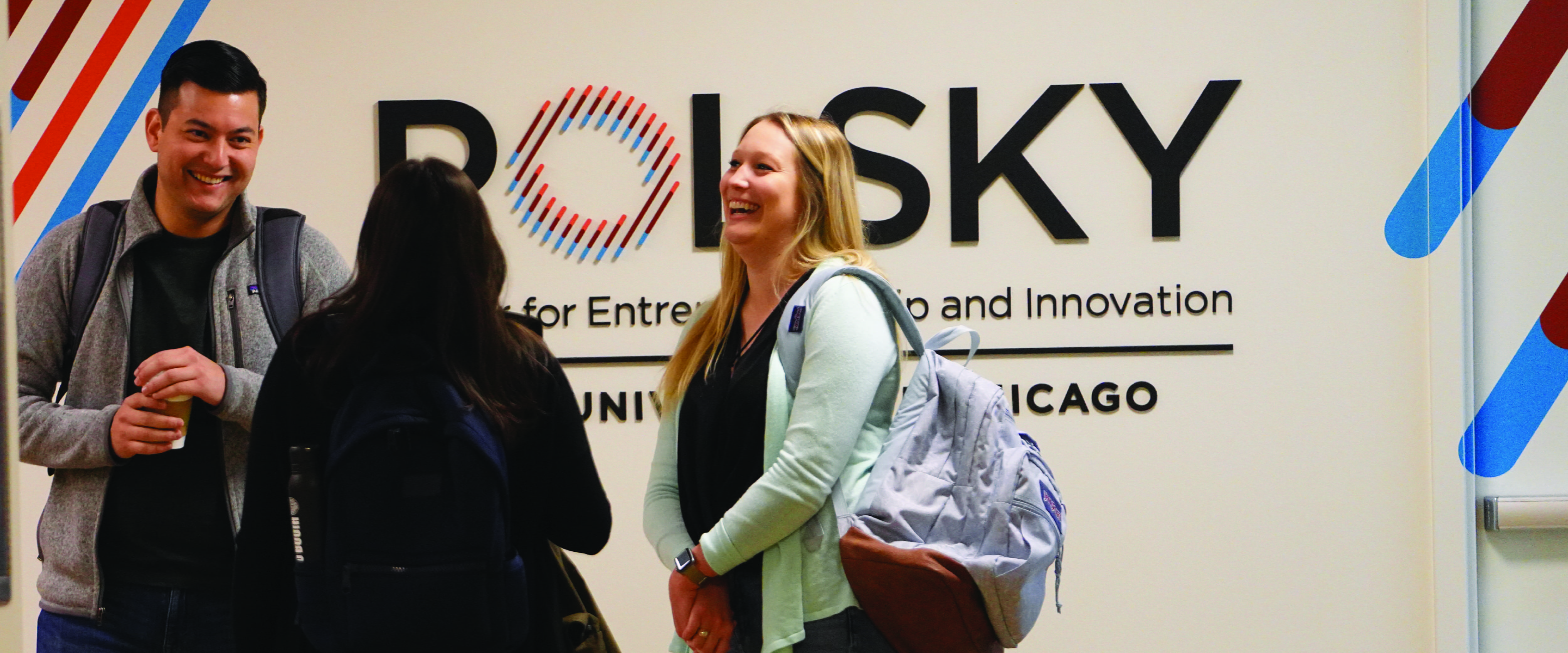Three Booth students chat in front of the Polsky Center
