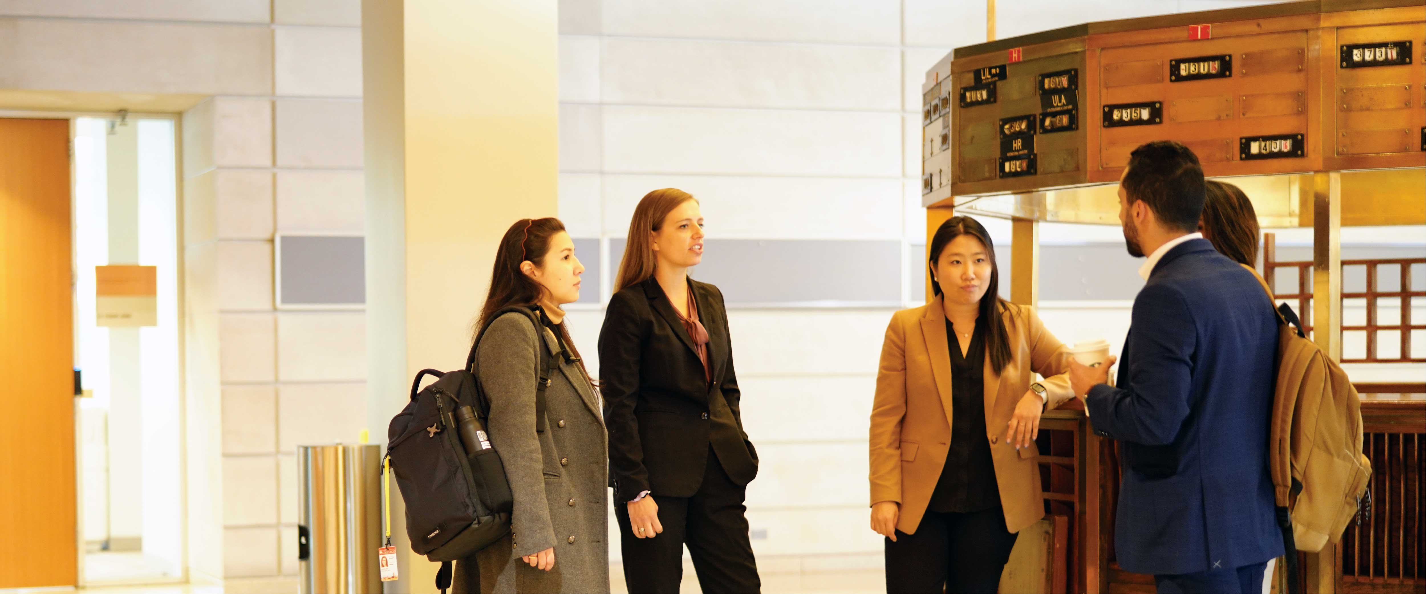 A group of Booth MBA students in professional dress, chatting in a group 
