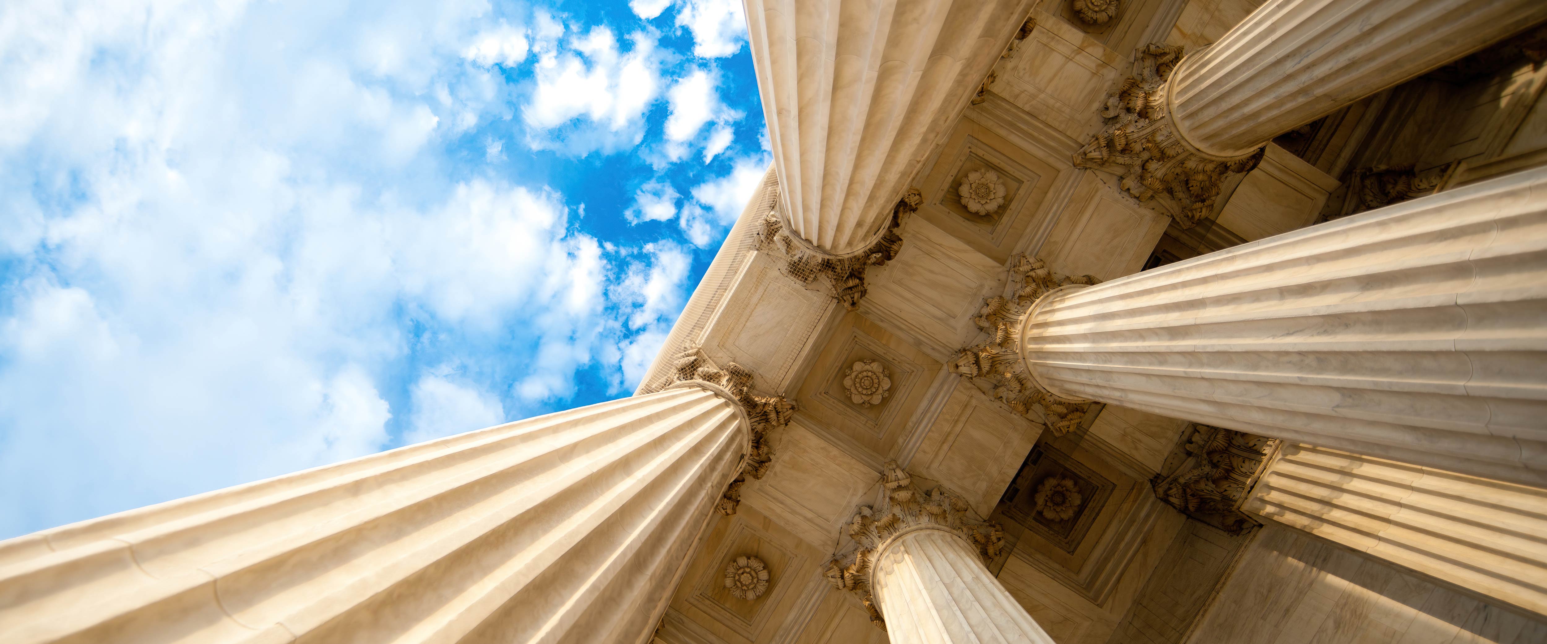 Looking up at the columns of a government building and a blue sky
