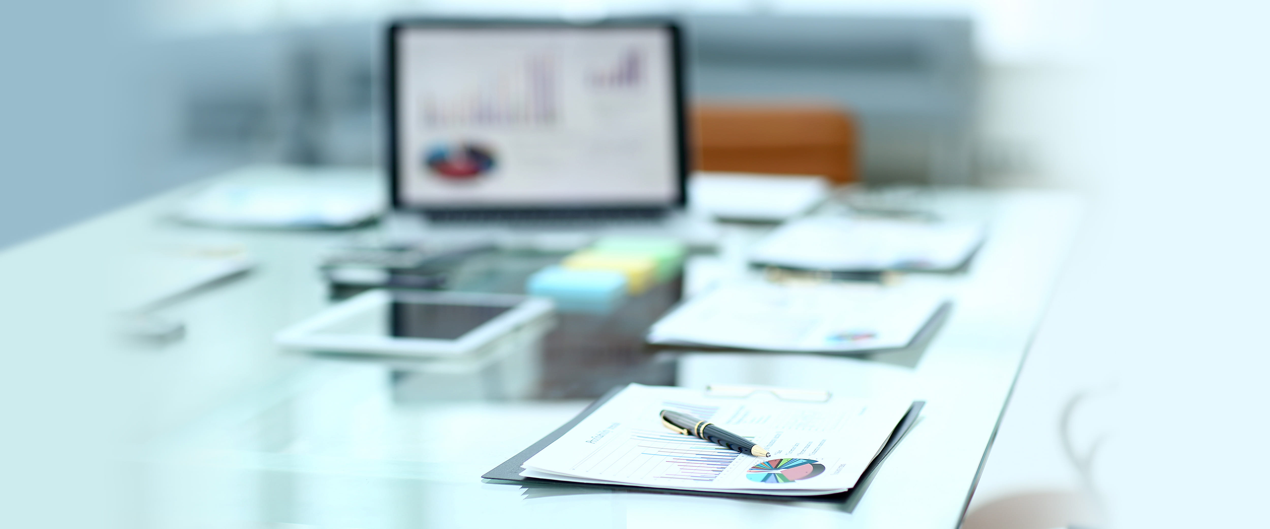 Accounting papers and a laptop on a glass desk