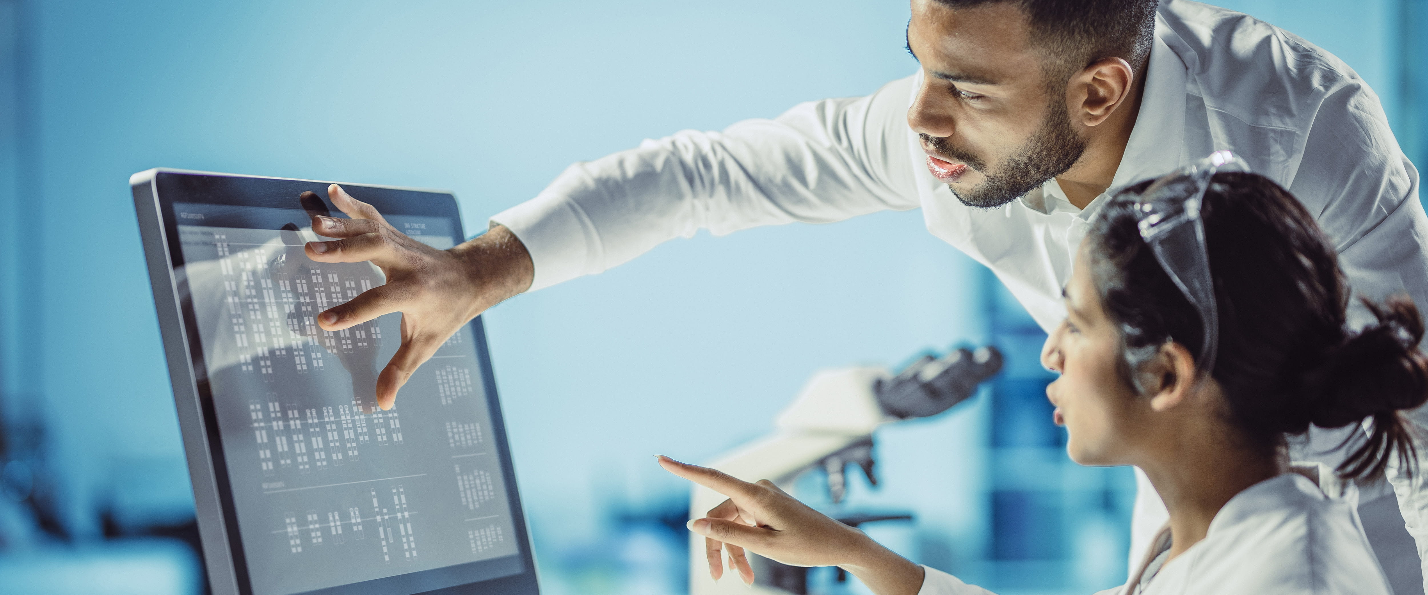 Two scientists pointing and analyzing data on a computer screen 