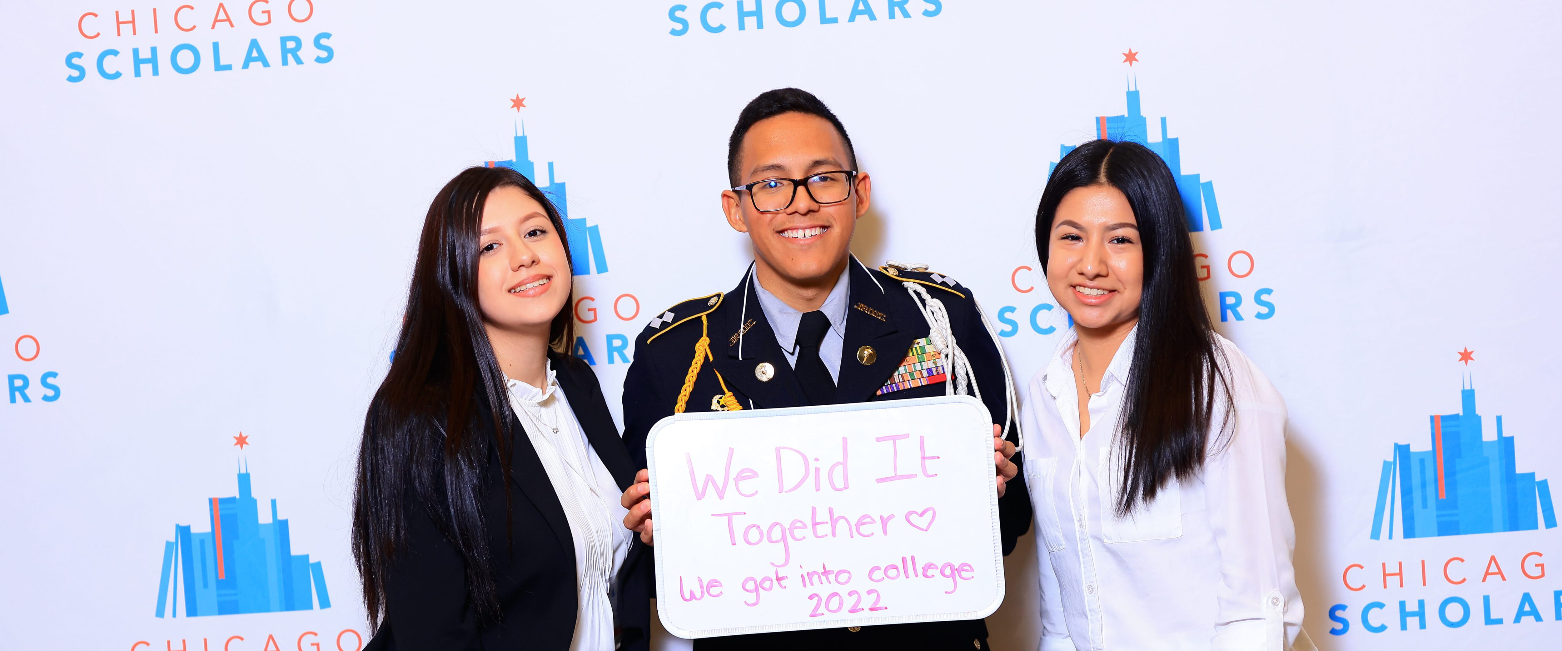 Three Chicago Booth Scholars pose with a "We Did It Together" sign