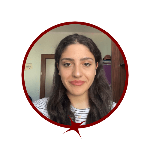 Picture of brunette woman wearing a light t-shirt and standing in front of a door. 