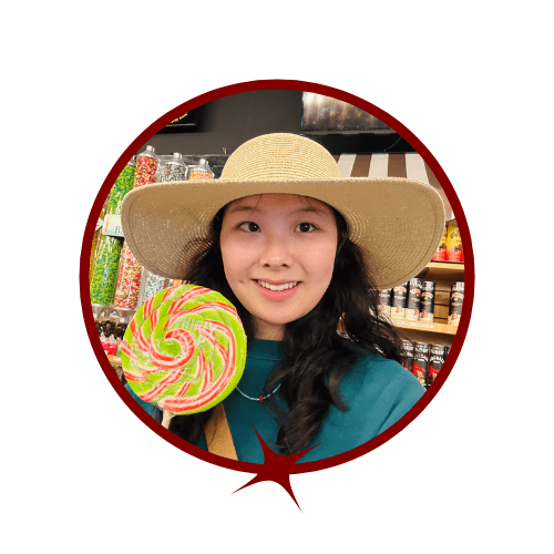 Picture of smiling, dark-haired woman in a straw hat holding a candy lollipop. 