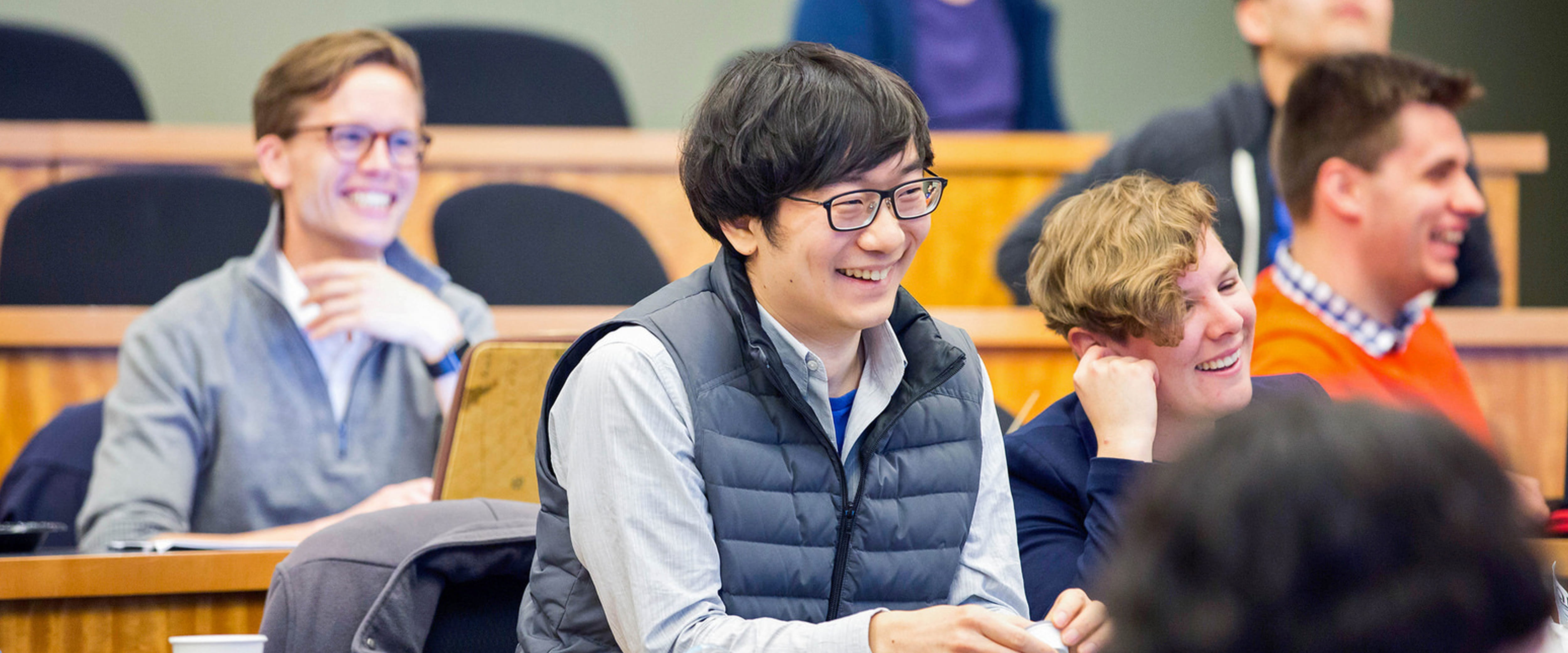 Diverse group of students laughing while attending lecture.