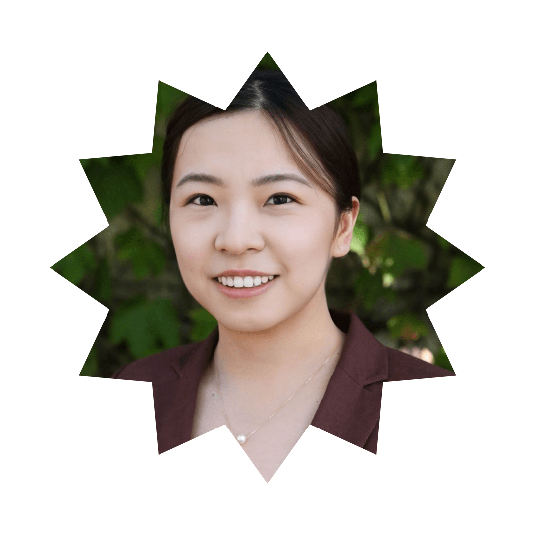 Picture of smiling dark-haired woman standing in front of a green vine background and wearing a pearl necklace. The picture is set in a star-shaped frame. 