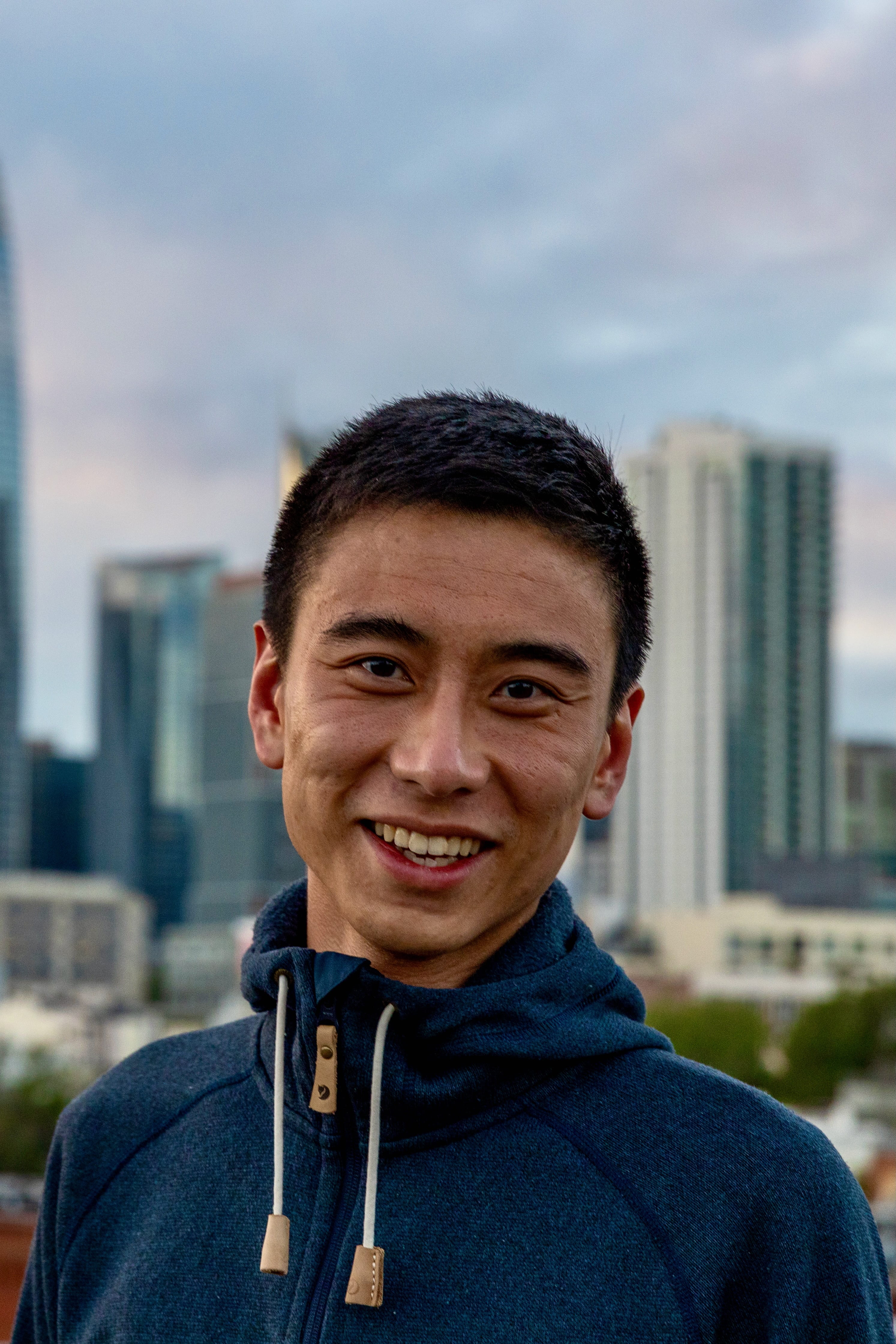 Headshot of PhD student, Walter Zhang, standing in front of Chicago skyline